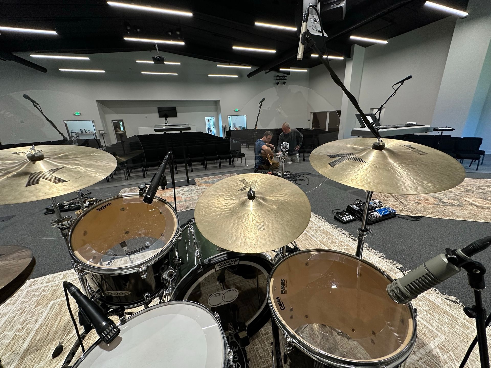 A drum set is sitting on a stage in a large room.
