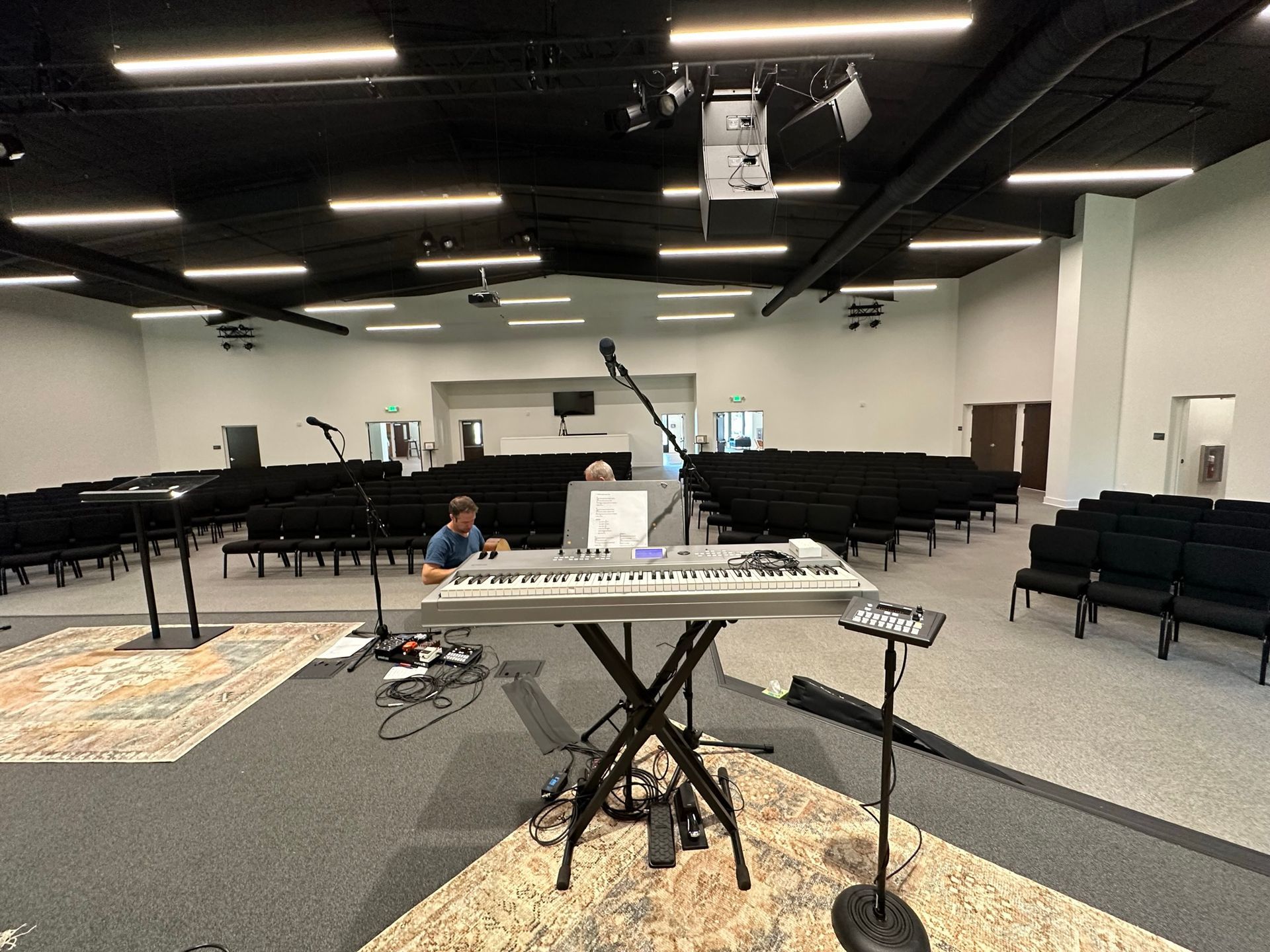 A man is sitting at a keyboard in a large room.
