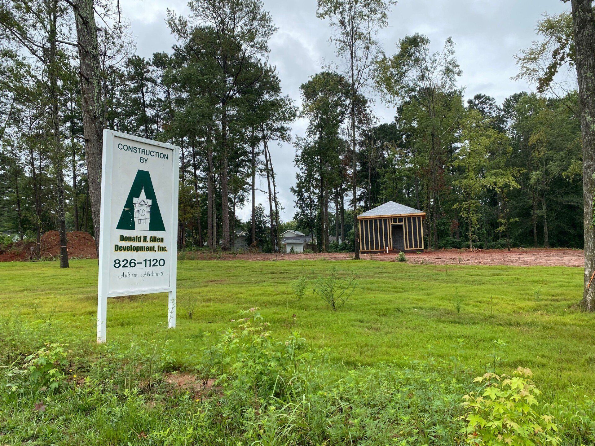 A sign in the middle of a grassy field with trees in the background.