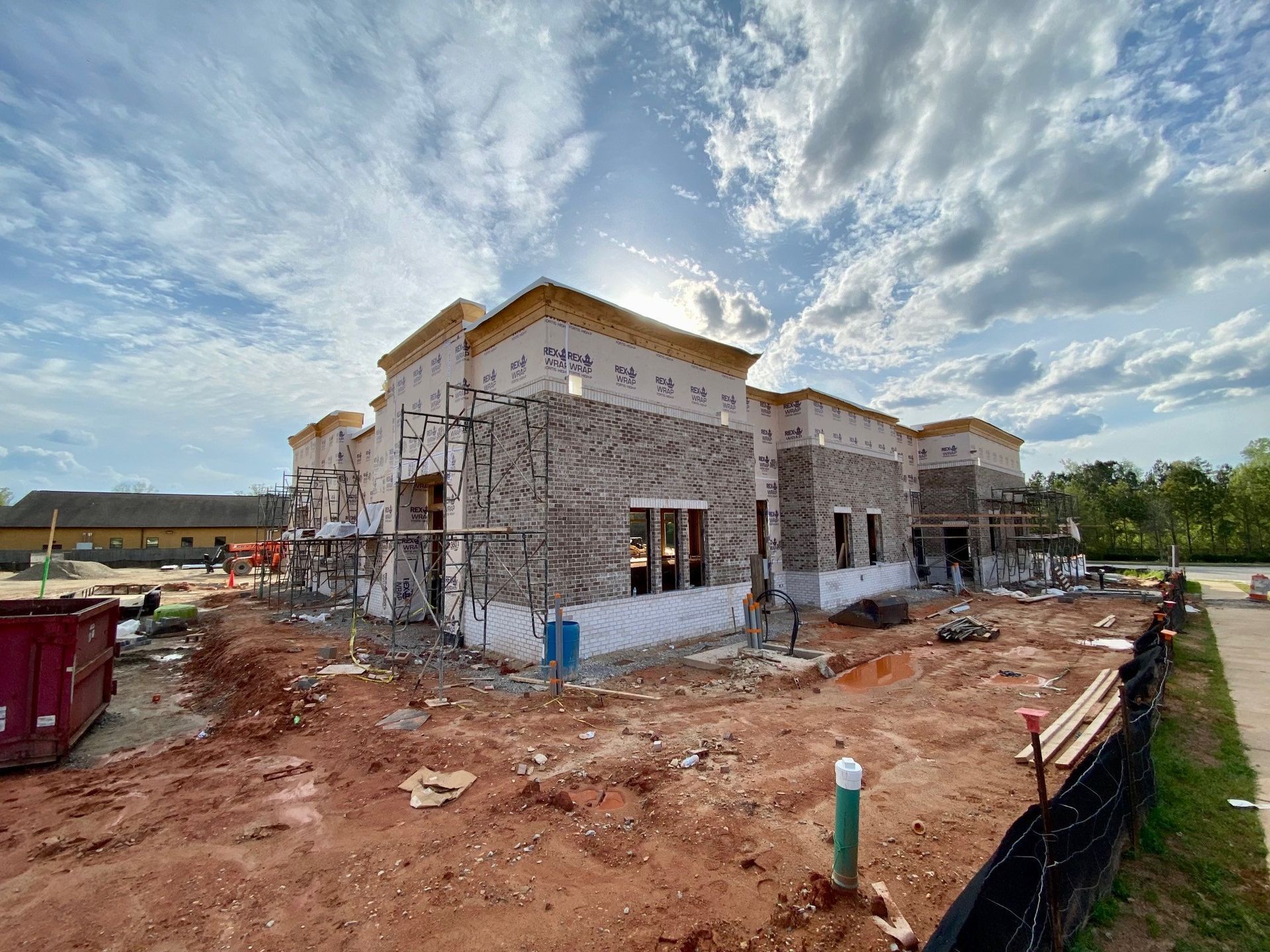 A large building is being built in the middle of a dirt field.