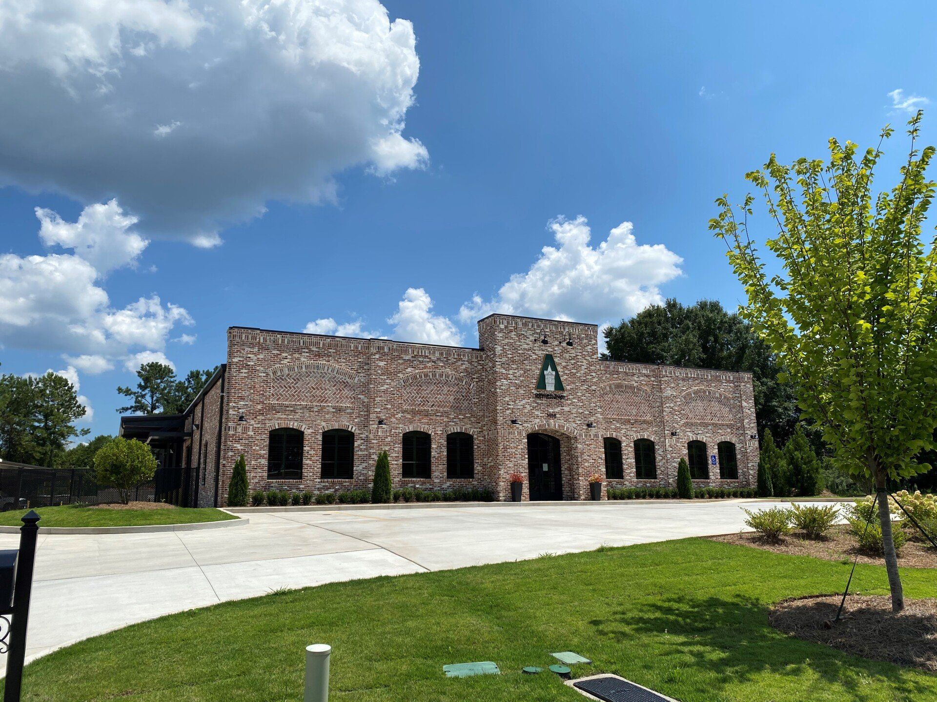 A large stone building with a lot of windows is sitting in the middle of a lush green field.