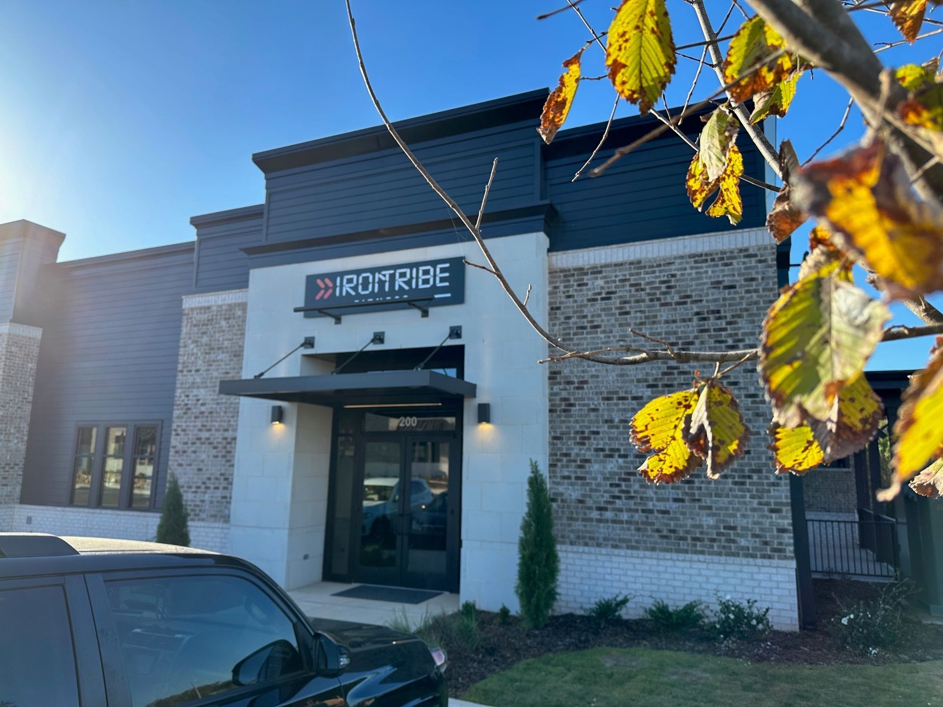A black car is parked in front of a building that says irontribe.