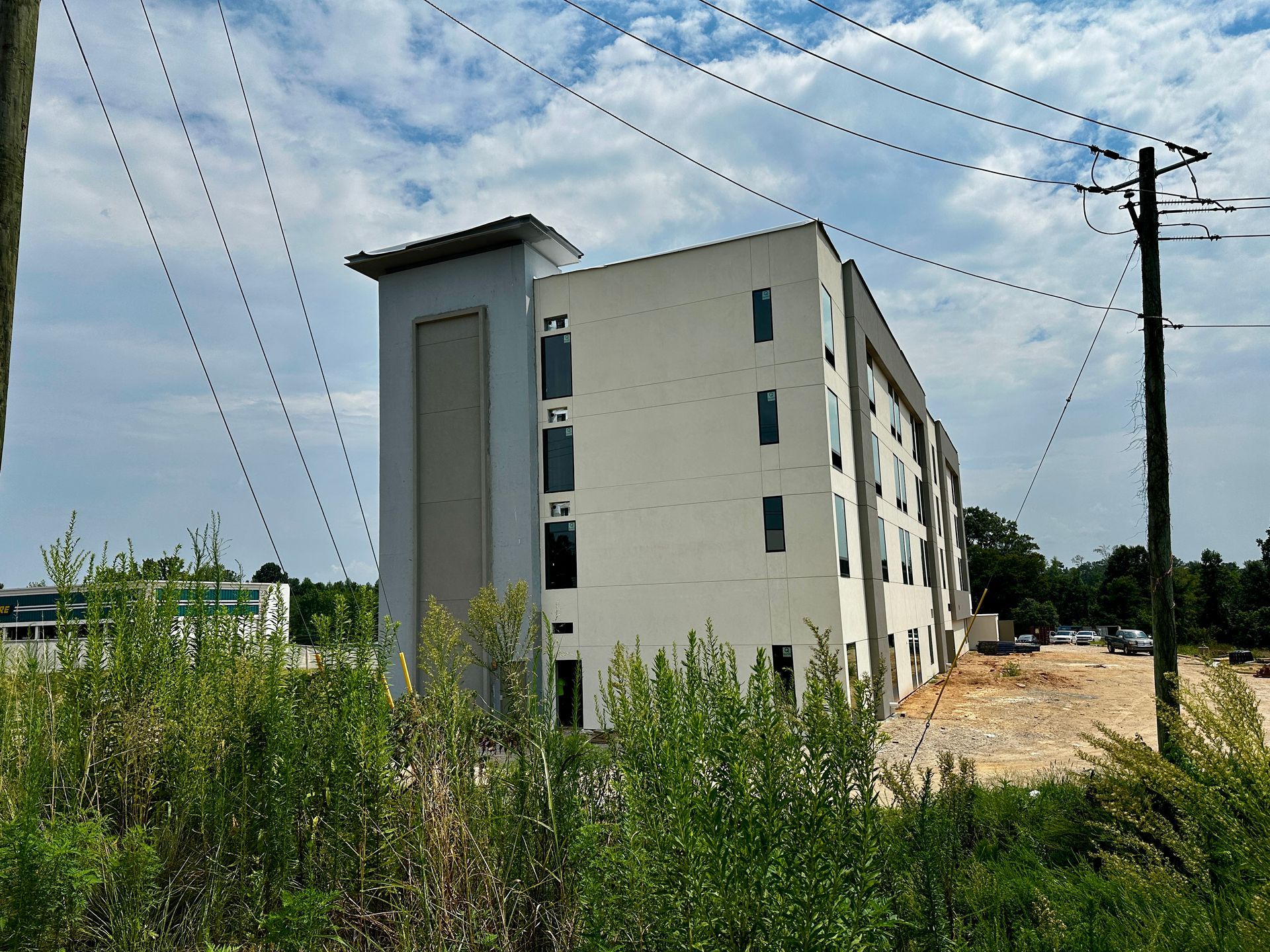 Partially built apartment building beside tall grass under a cloudy sky