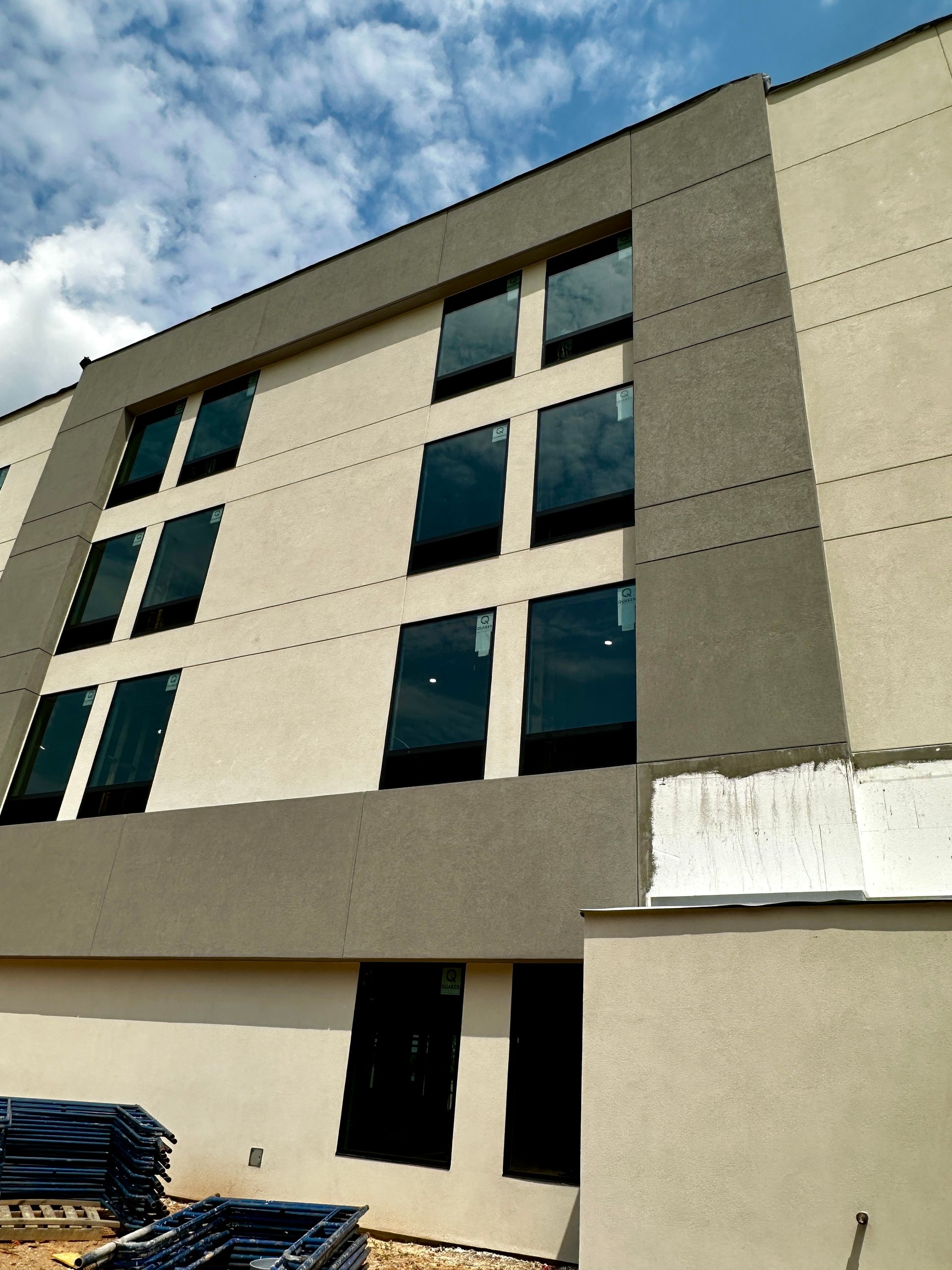 Exterior of a beige multi-story building with large windows against a blue sky