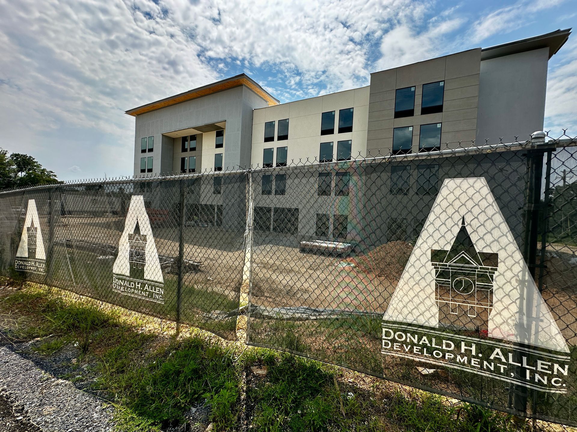 Modern building behind a chain-link fence with large A letters and a star sign in front