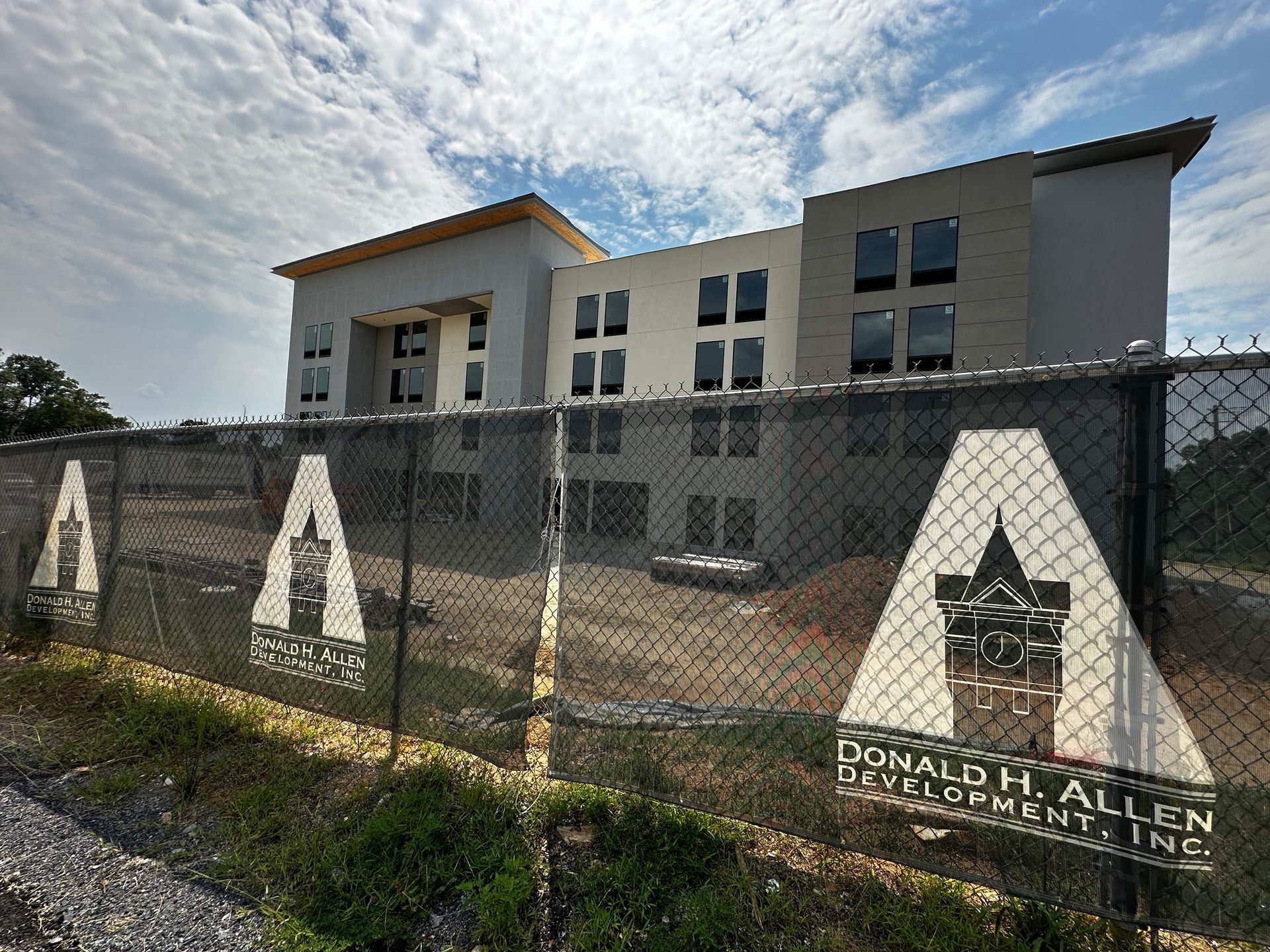 A modern building behind a chain-link fence with large “A” signs and a Donald H. Allen School sign.