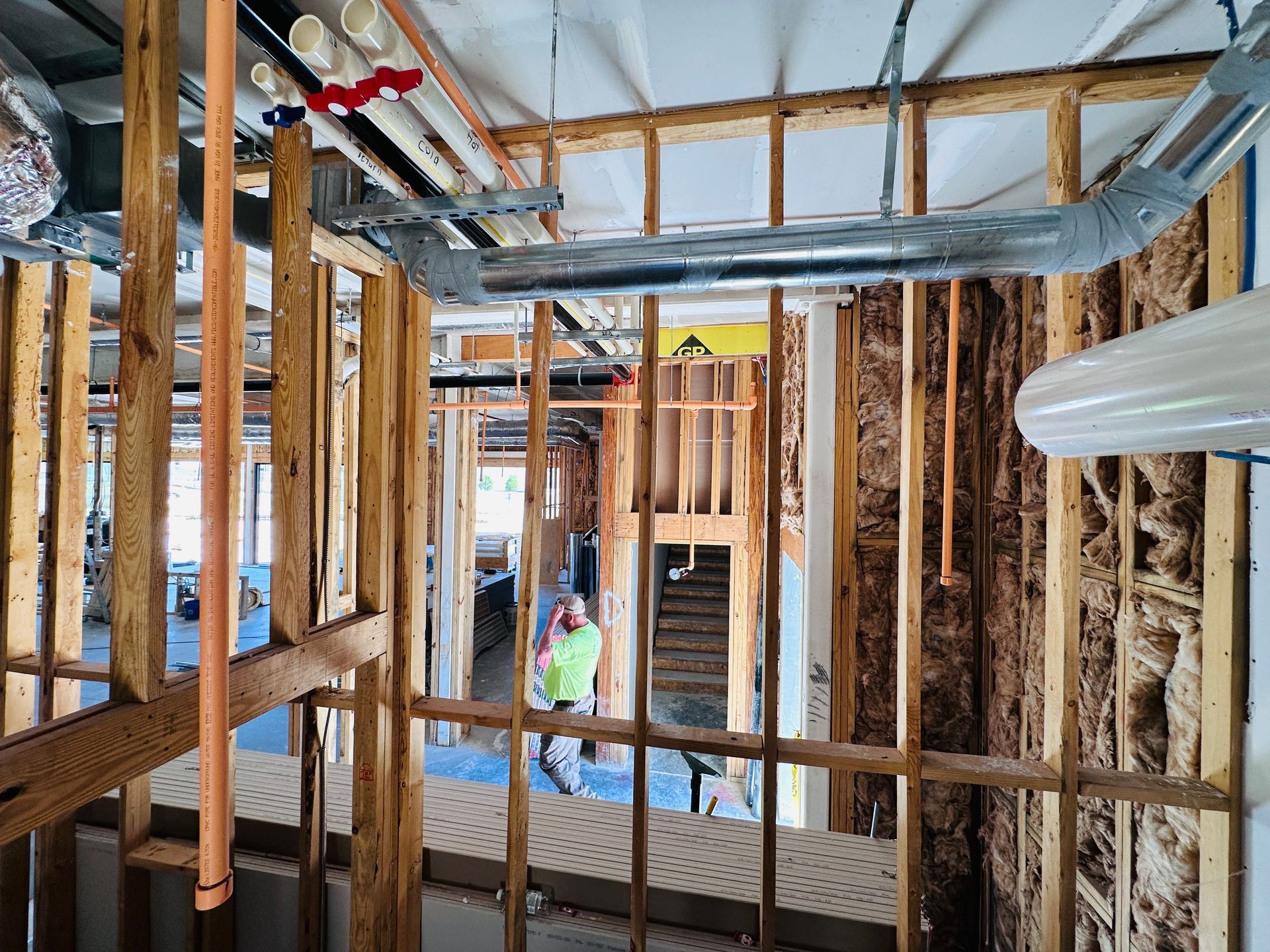 Interior of a hotel under construction with exposed wood framing, insulation, and ductwork visible.