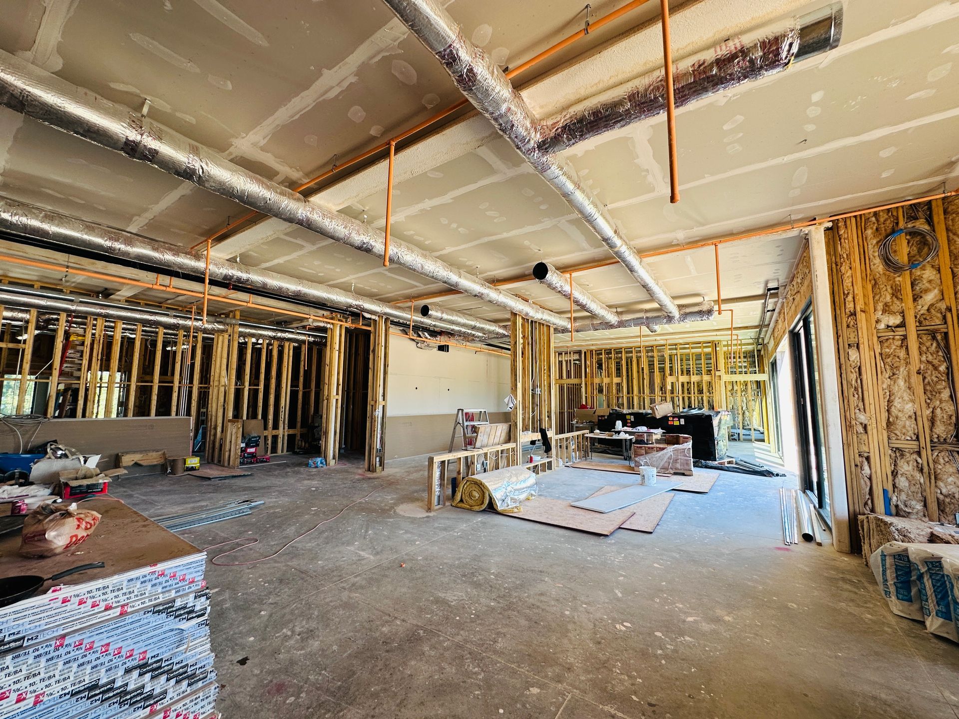 Interior of unfinished room with exposed ducts, insulation, and construction materials scattered on the floor.