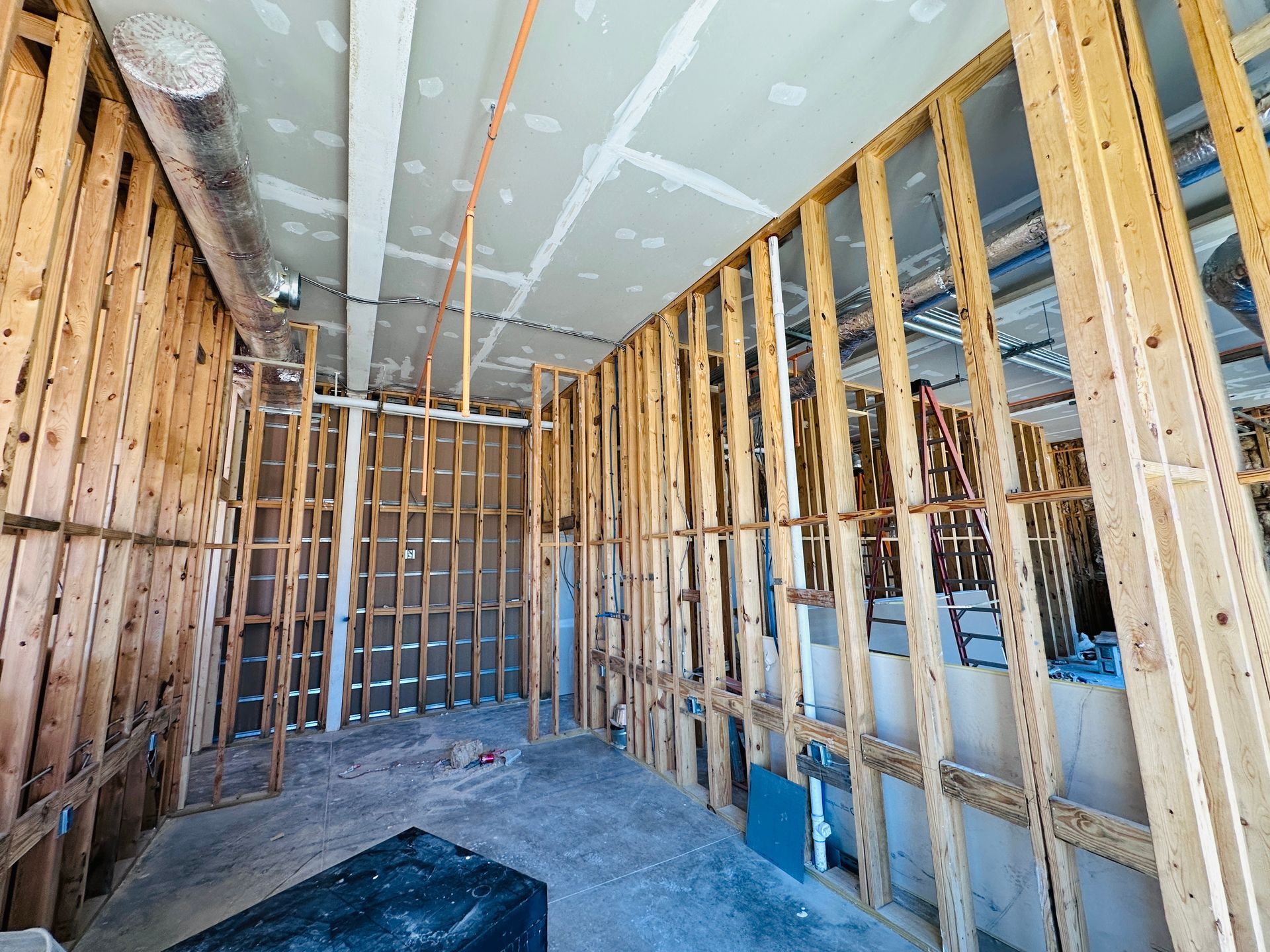 Unfinished room with exposed wood framing, drywall ceiling, and blue utility boxes on the right