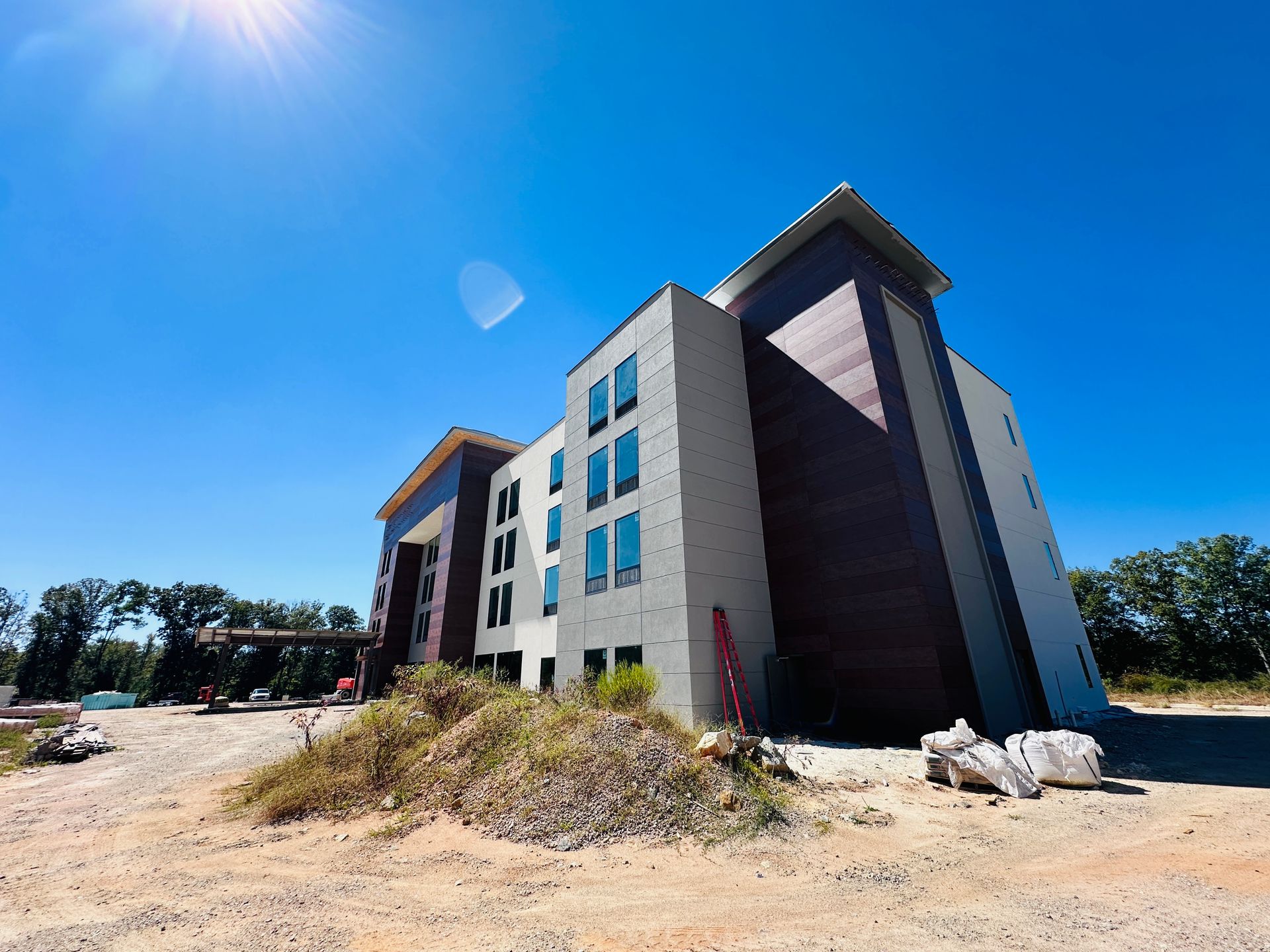 Modern multi-story building with blue windows and dark siding under a bright blue sky