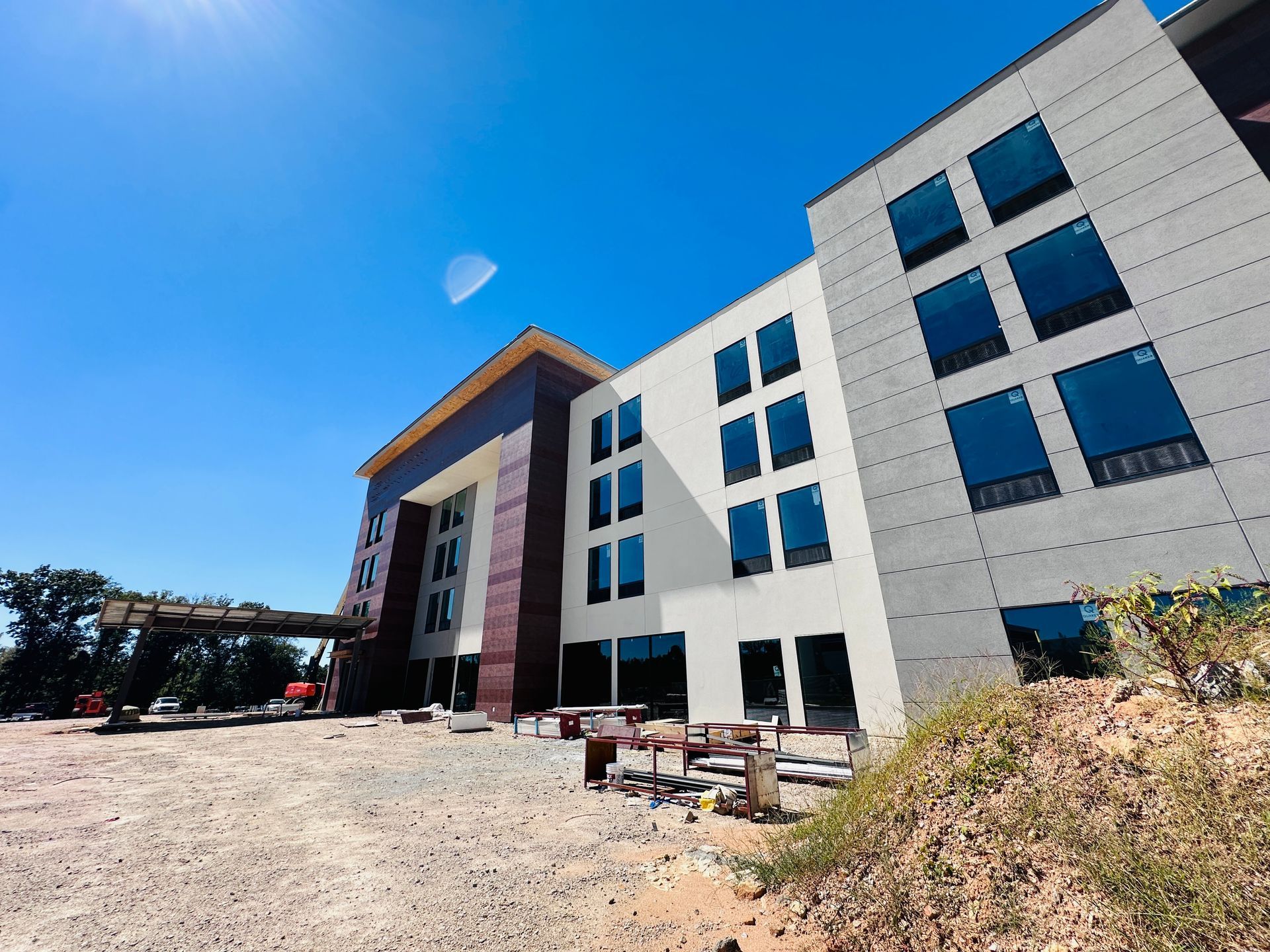 Modern multi-story building under construction with white and blue facade and gravel foreground