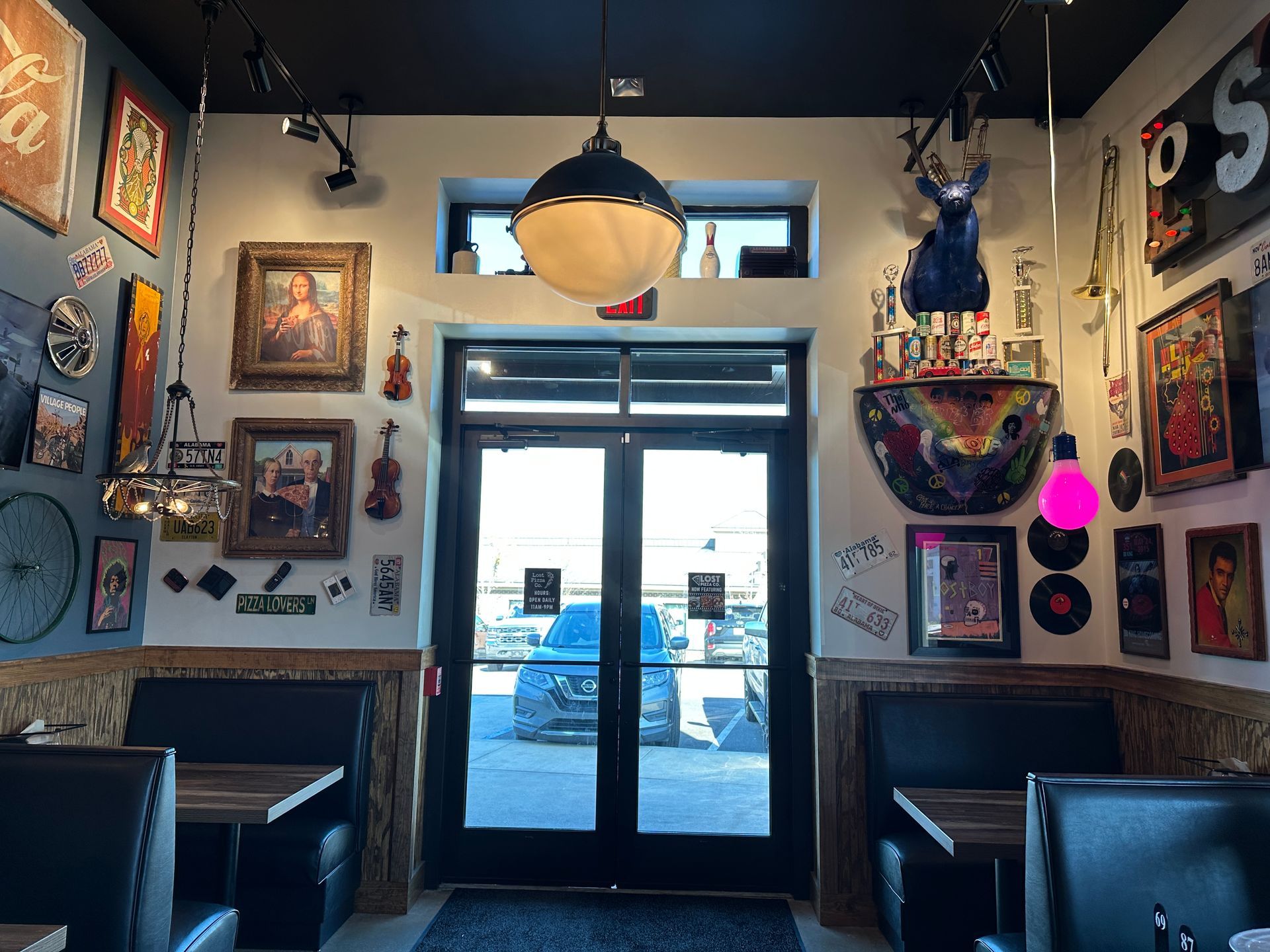 Restaurant interior with decorated walls, booth seating, and double doors to the outside.