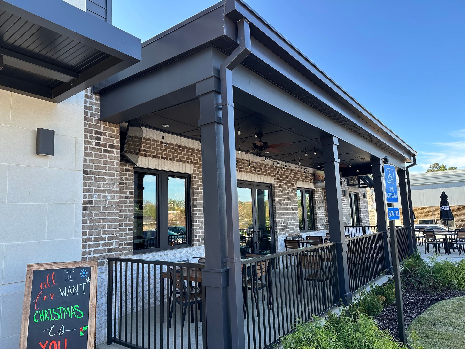 Exterior of a restaurant with a covered patio, brick and black accents, and outdoor seating.