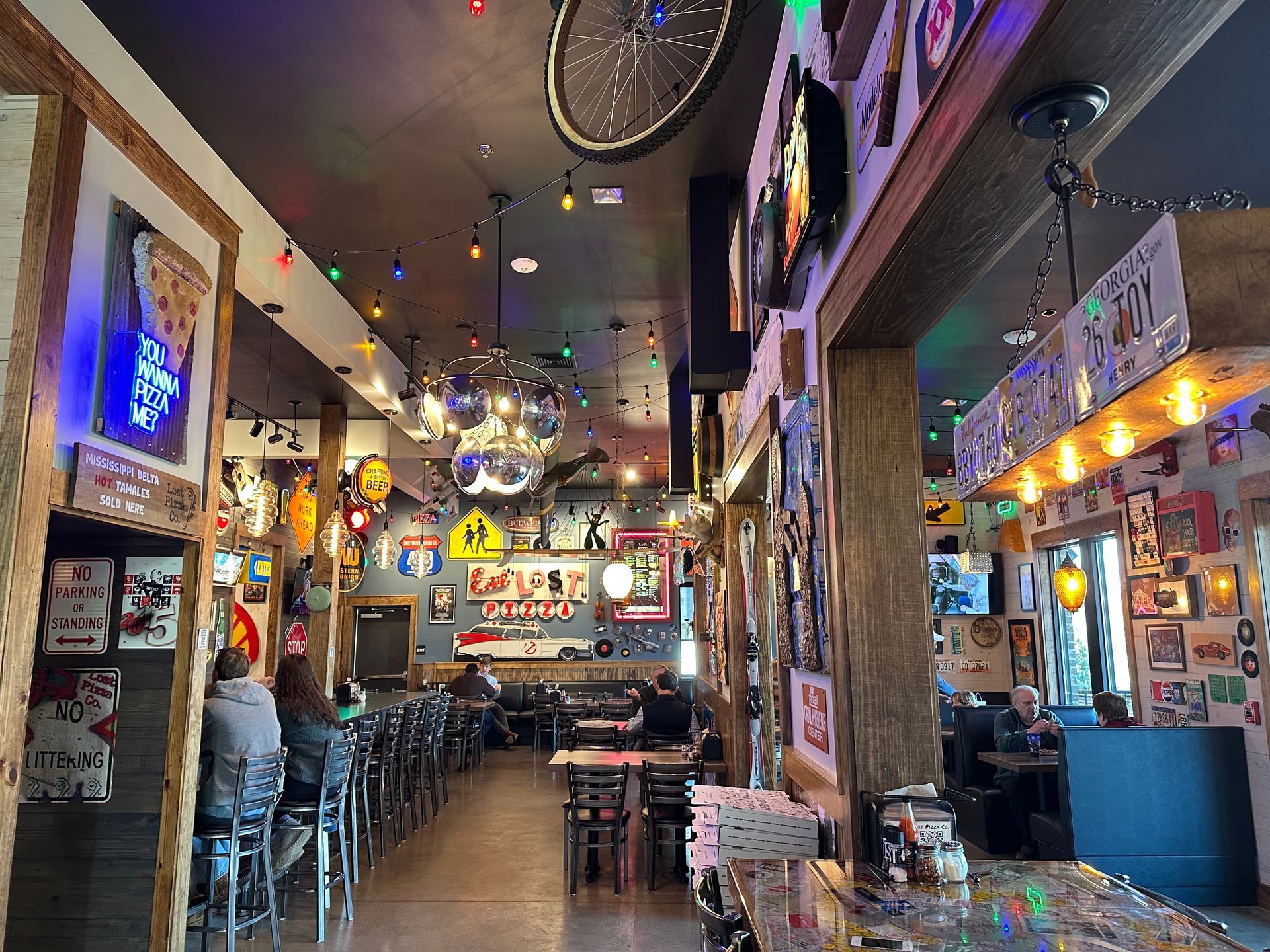 Interior of a restaurant with bar seating, tables, decorations, and people dining.