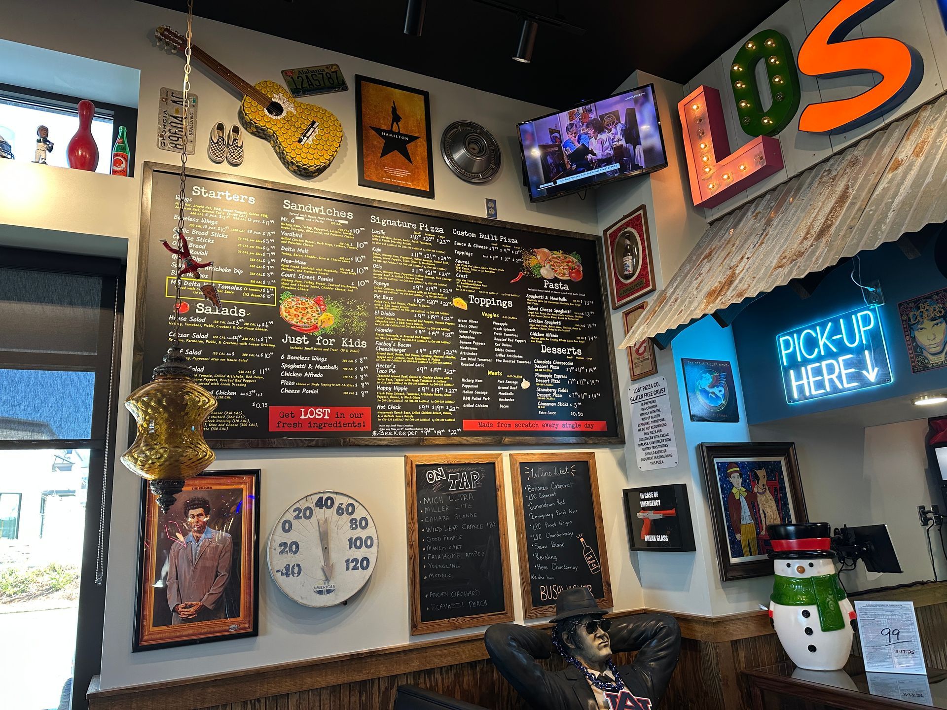 Interior of a restaurant with a large menu board, decor including a guitar, and a television.