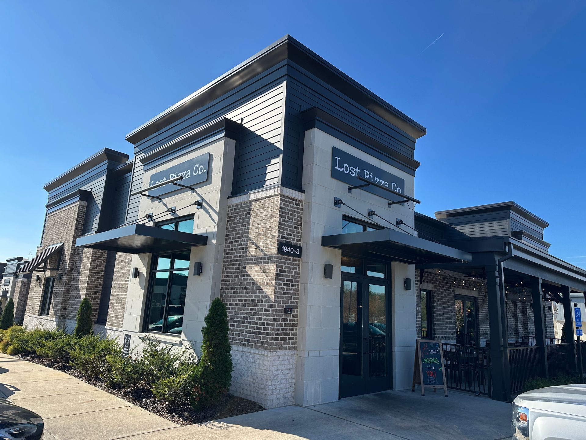 Restaurant with gray and brick facade under a clear blue sky.