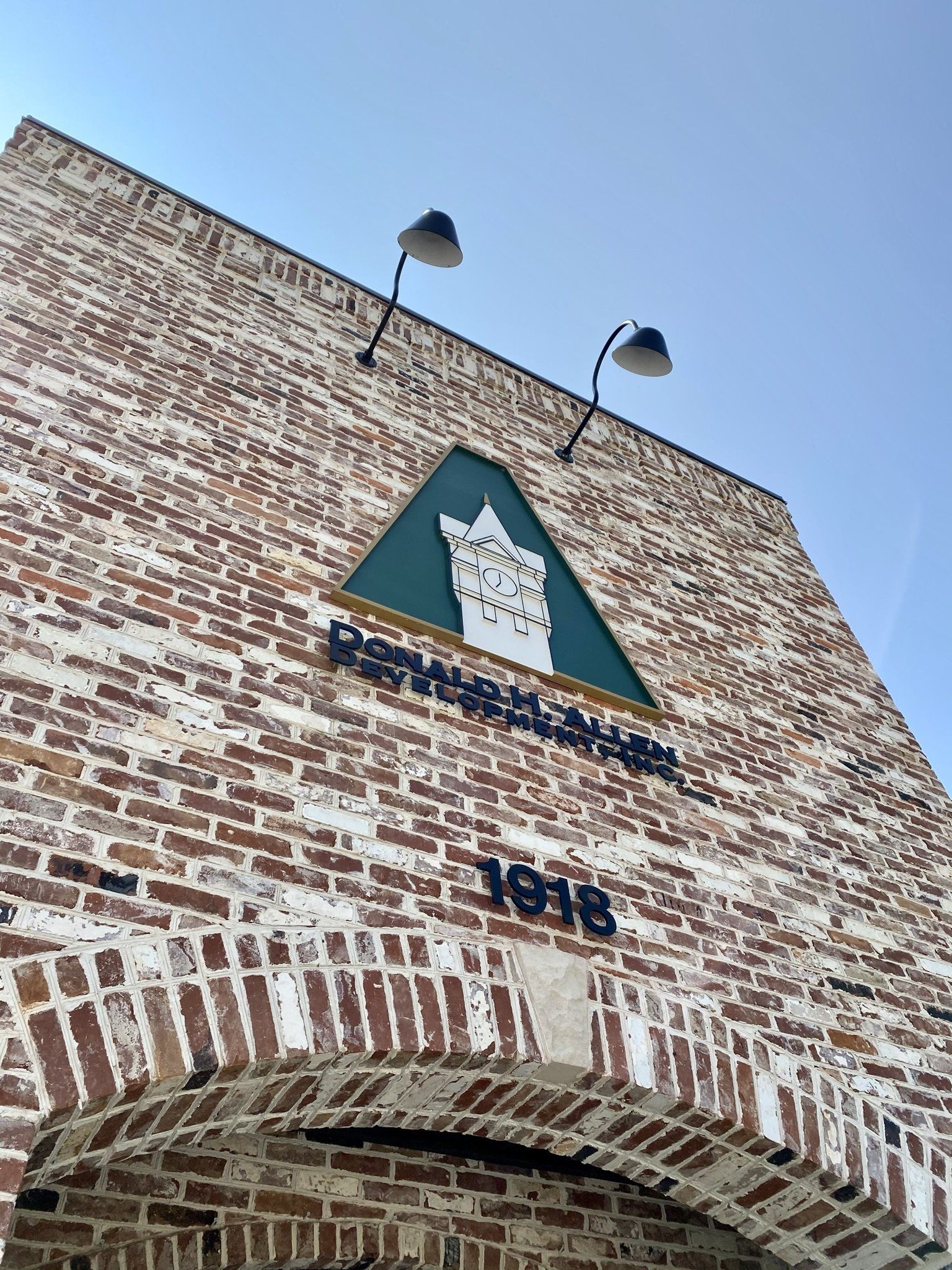 A brick building with a green triangle and the year 1916 on it.