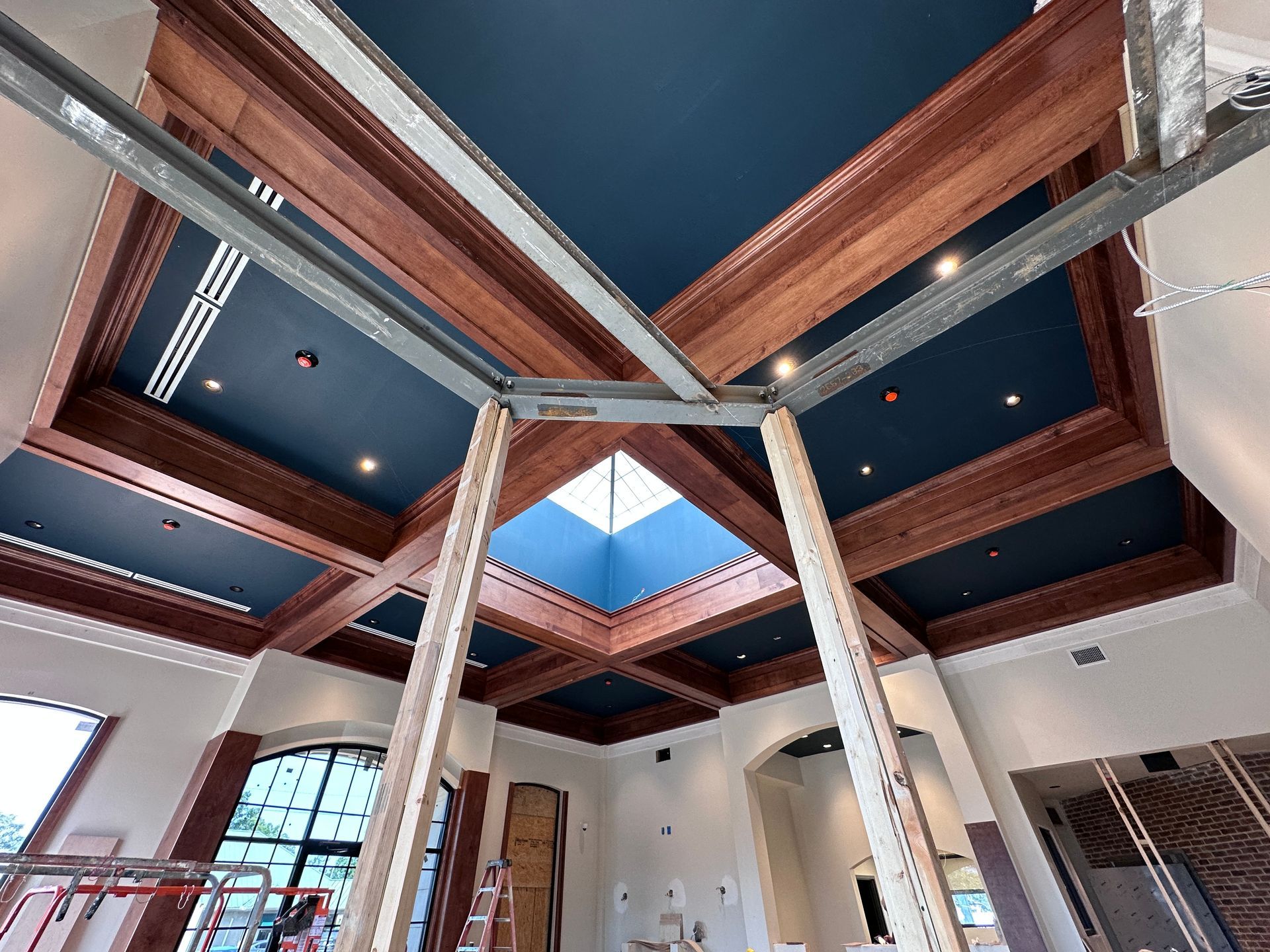 Wood-paneled ceiling with skylight and recessed lights above a room under construction