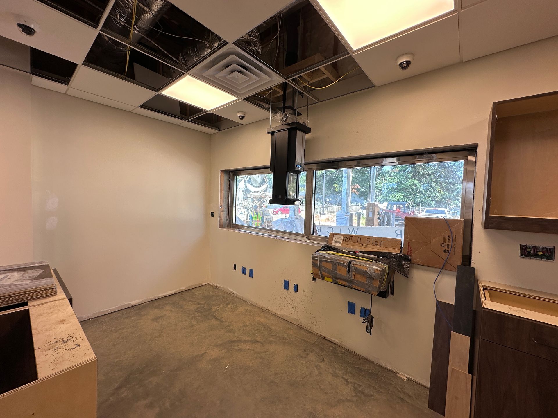 Empty room under renovation with exposed ceiling, window, and construction materials along the walls.