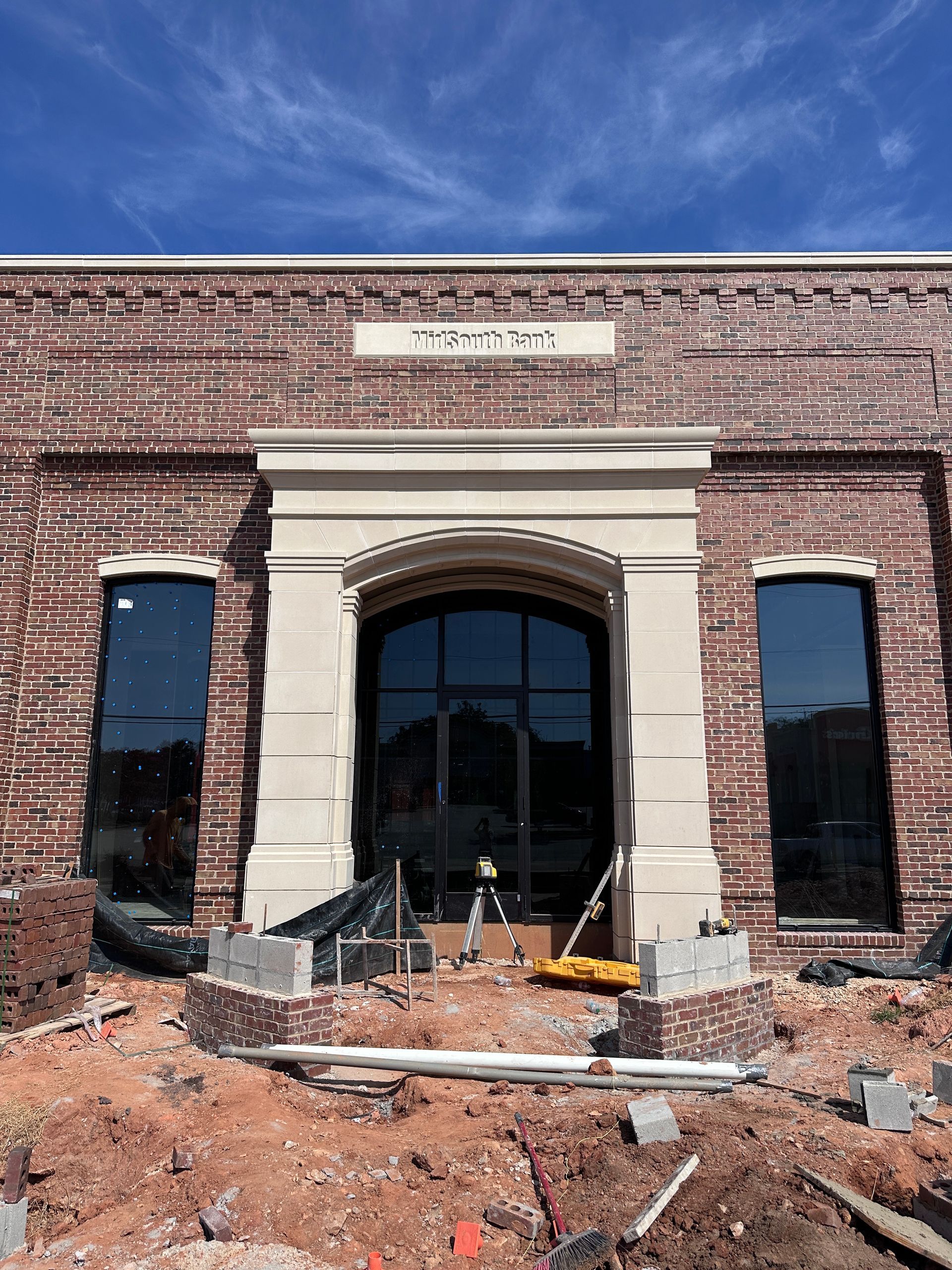Brick building under construction with damaged front entry and debris in the foreground