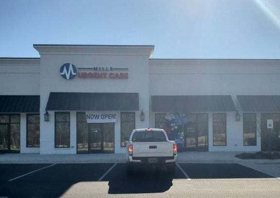 A white truck is parked in front of a building that says urgent care