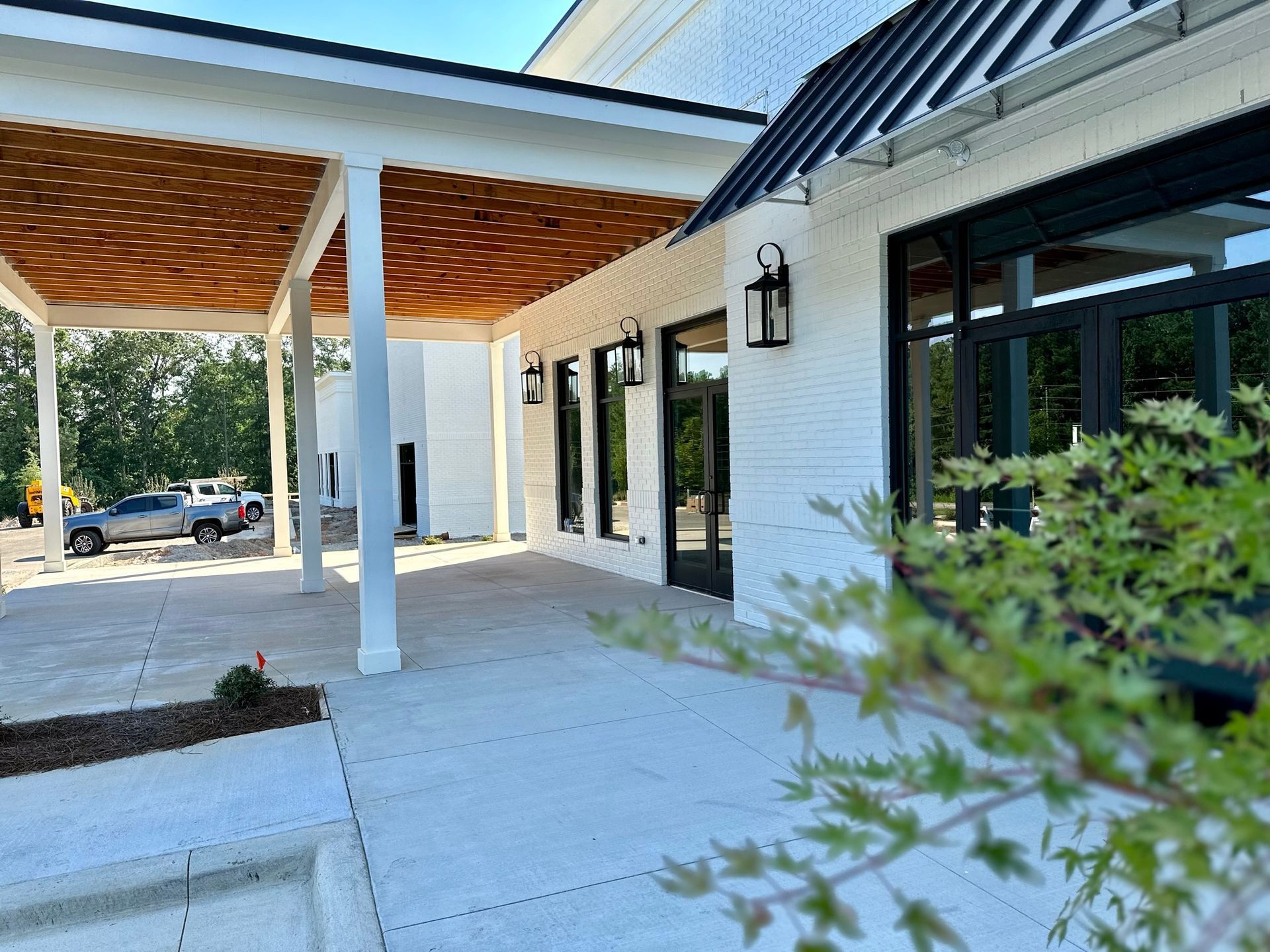 A white building with a porch and a tree in front of it.