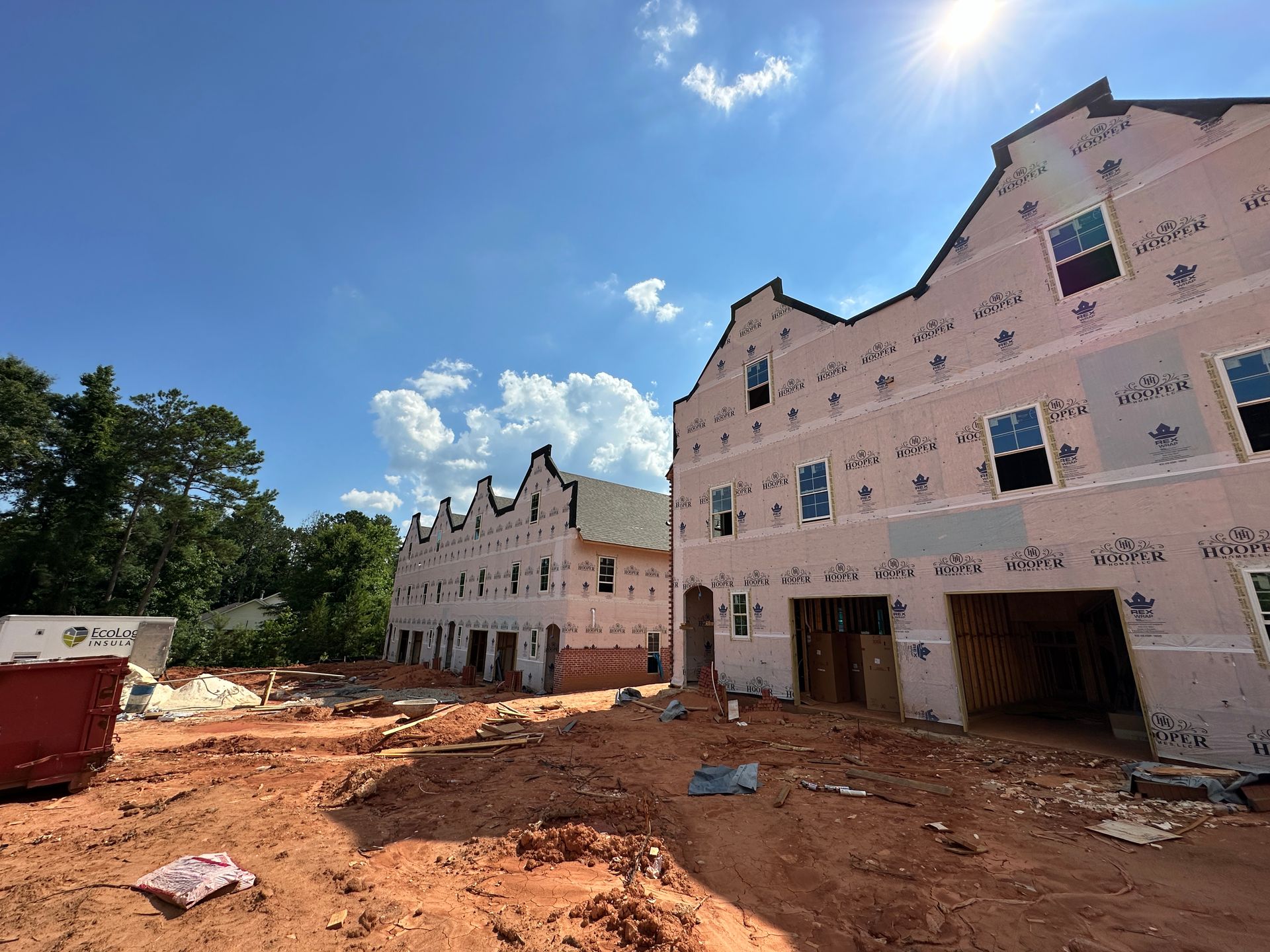A building under construction with a lot of windows and a lot of dirt in front of it.