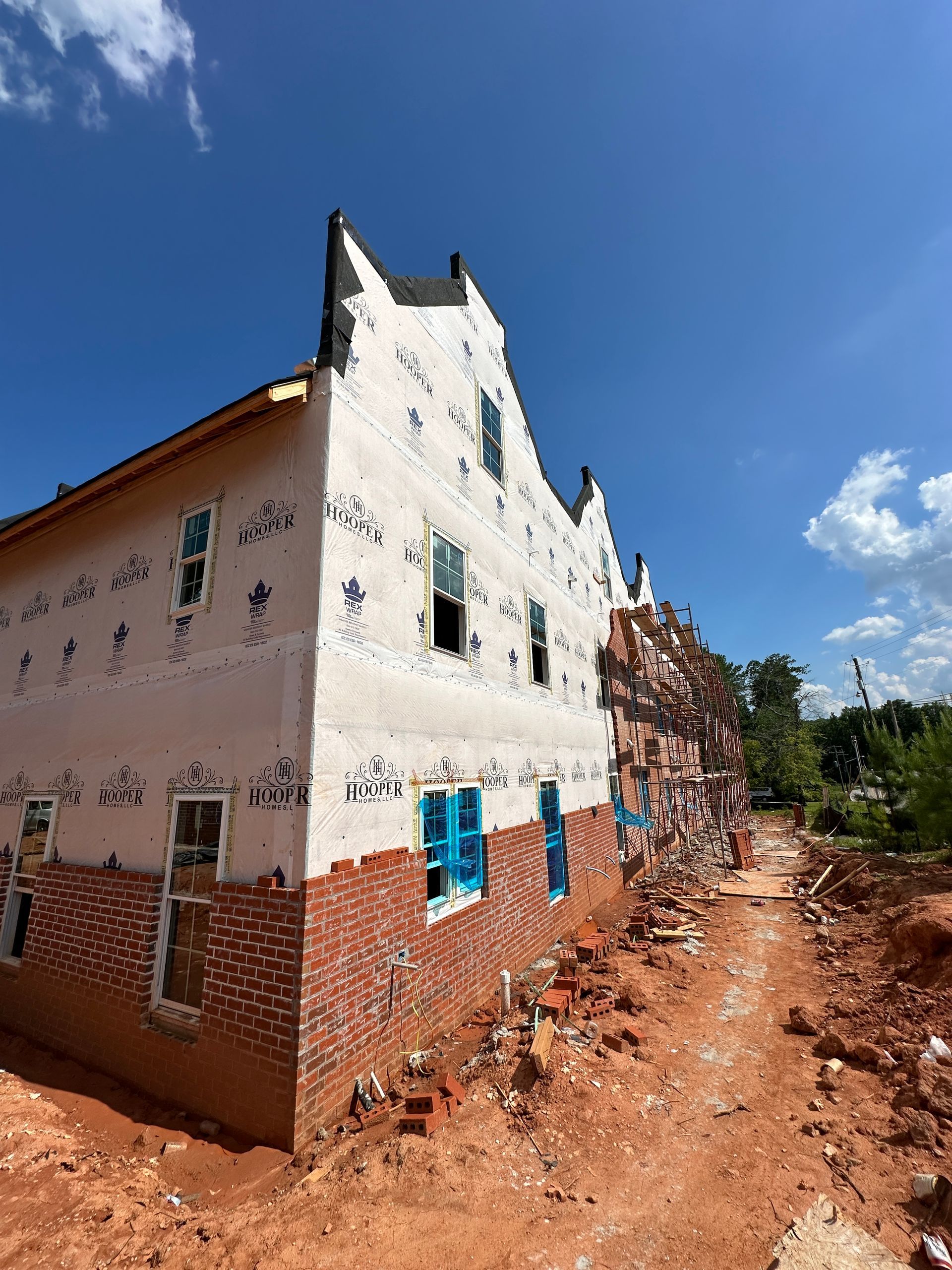 A large white building is being built in the middle of a dirt field.
