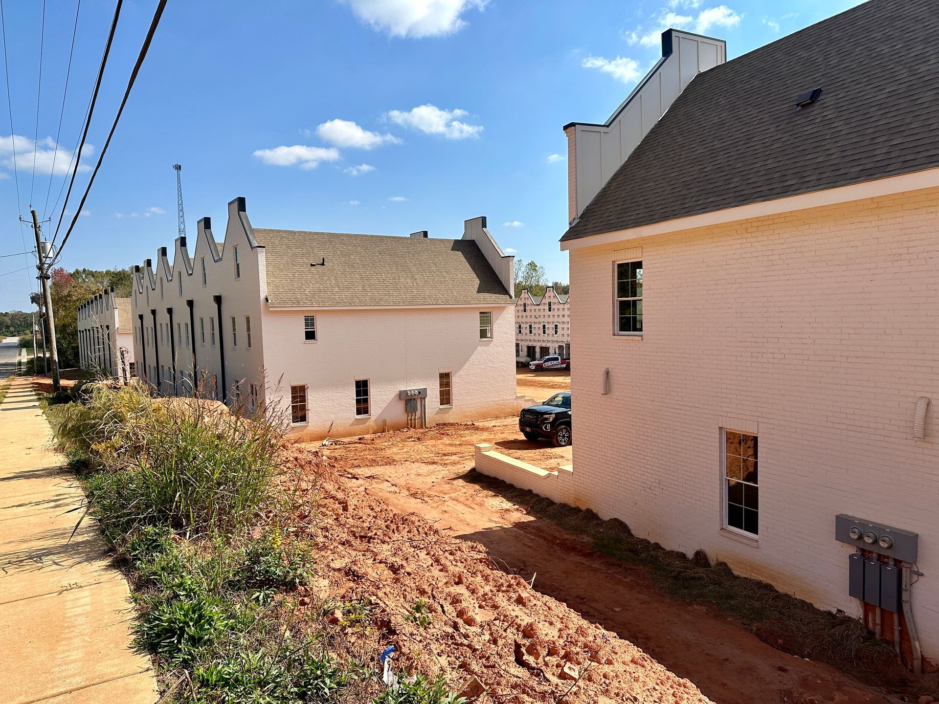 A row of white houses sitting next to each other on a dirt road
