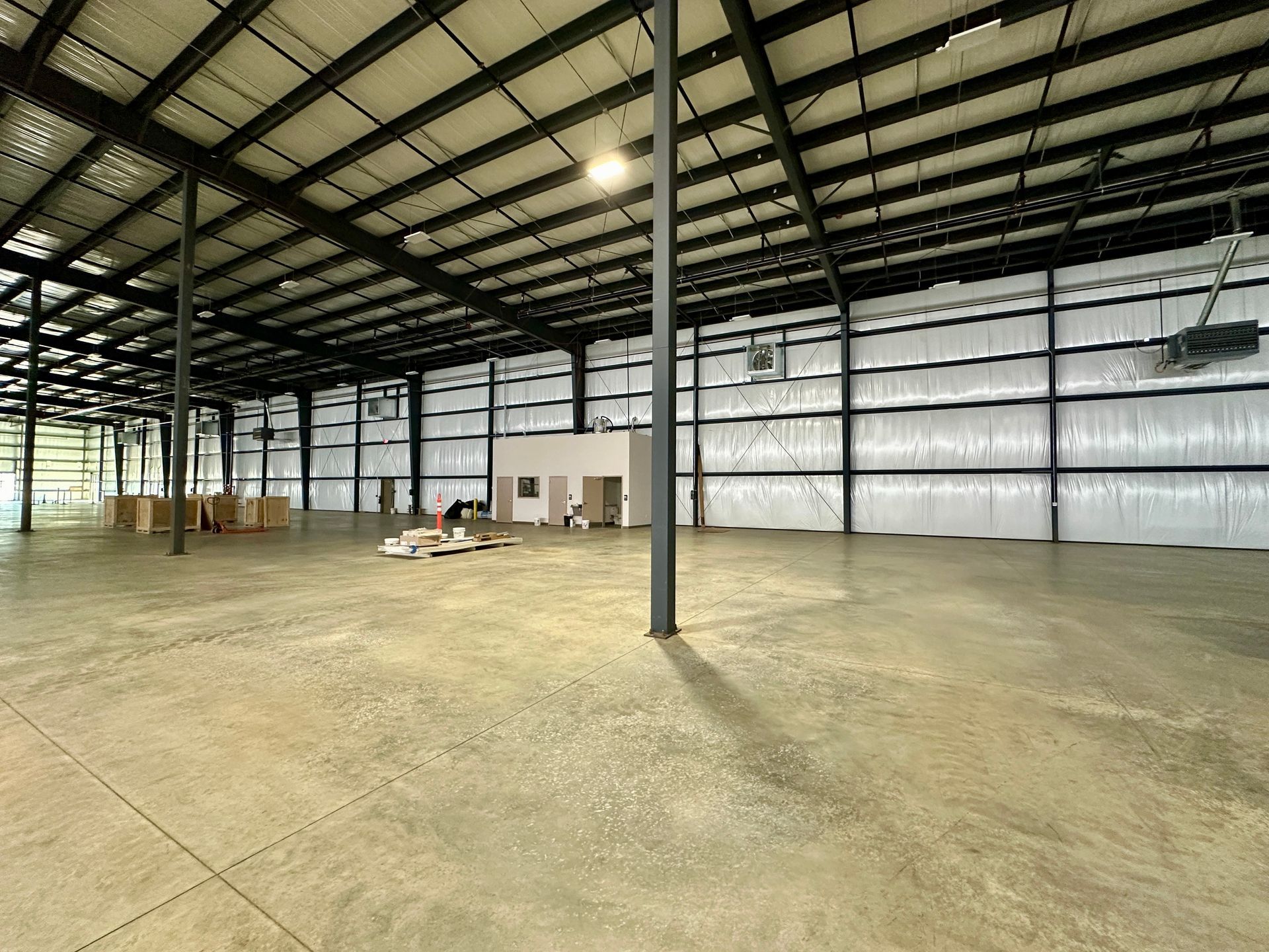 A large empty warehouse with a concrete floor and a metal roof.