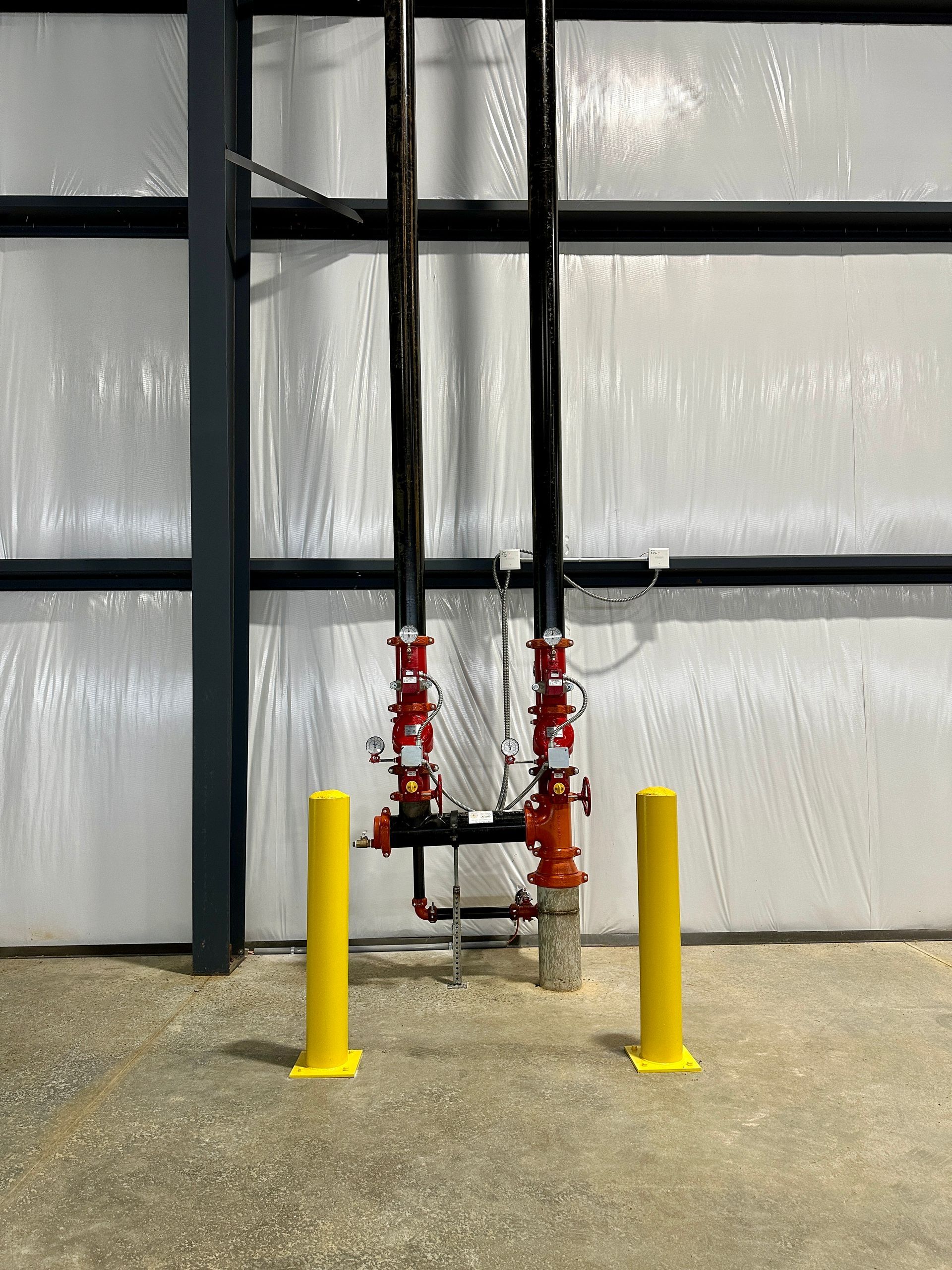Two yellow poles are sitting next to a fire hydrant in a building.
