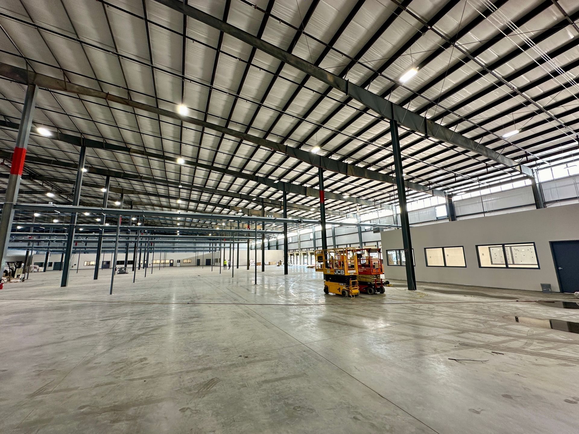 A large warehouse with a forklift in the middle of it.