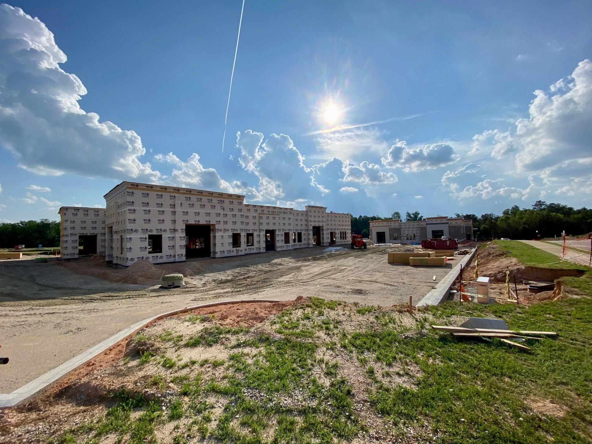 A large building under construction with the sun shining through the clouds