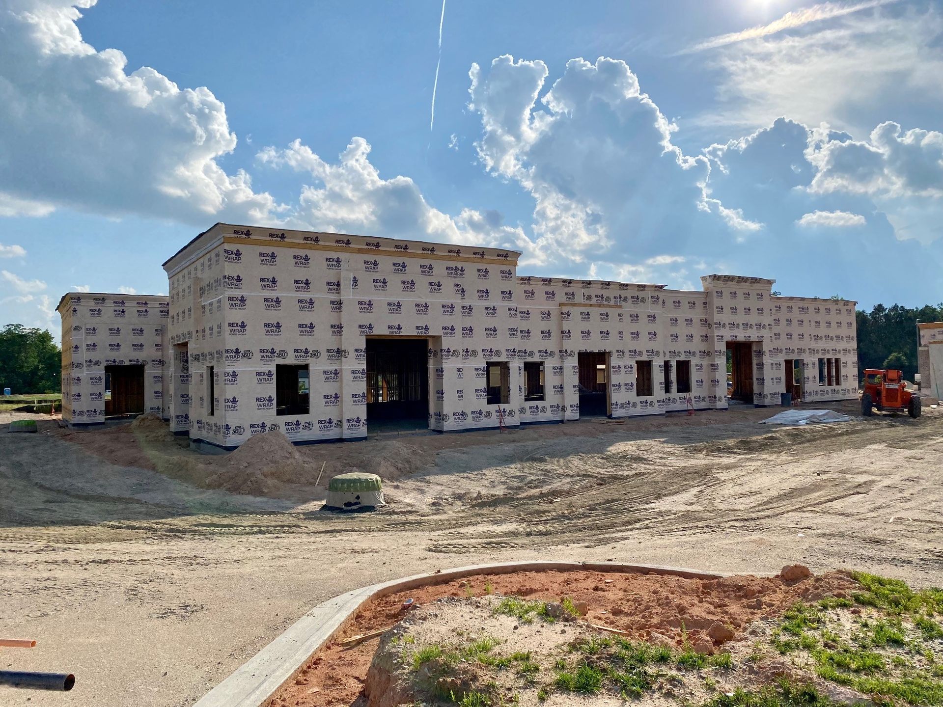 A large building is being built in the middle of a dirt field.