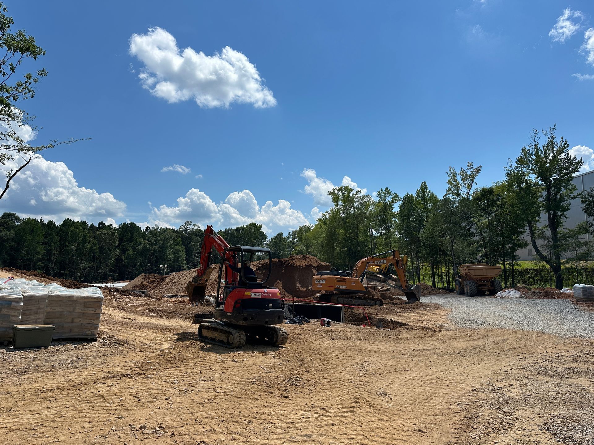 Construction site with excavators and dirt piles under a blue sky