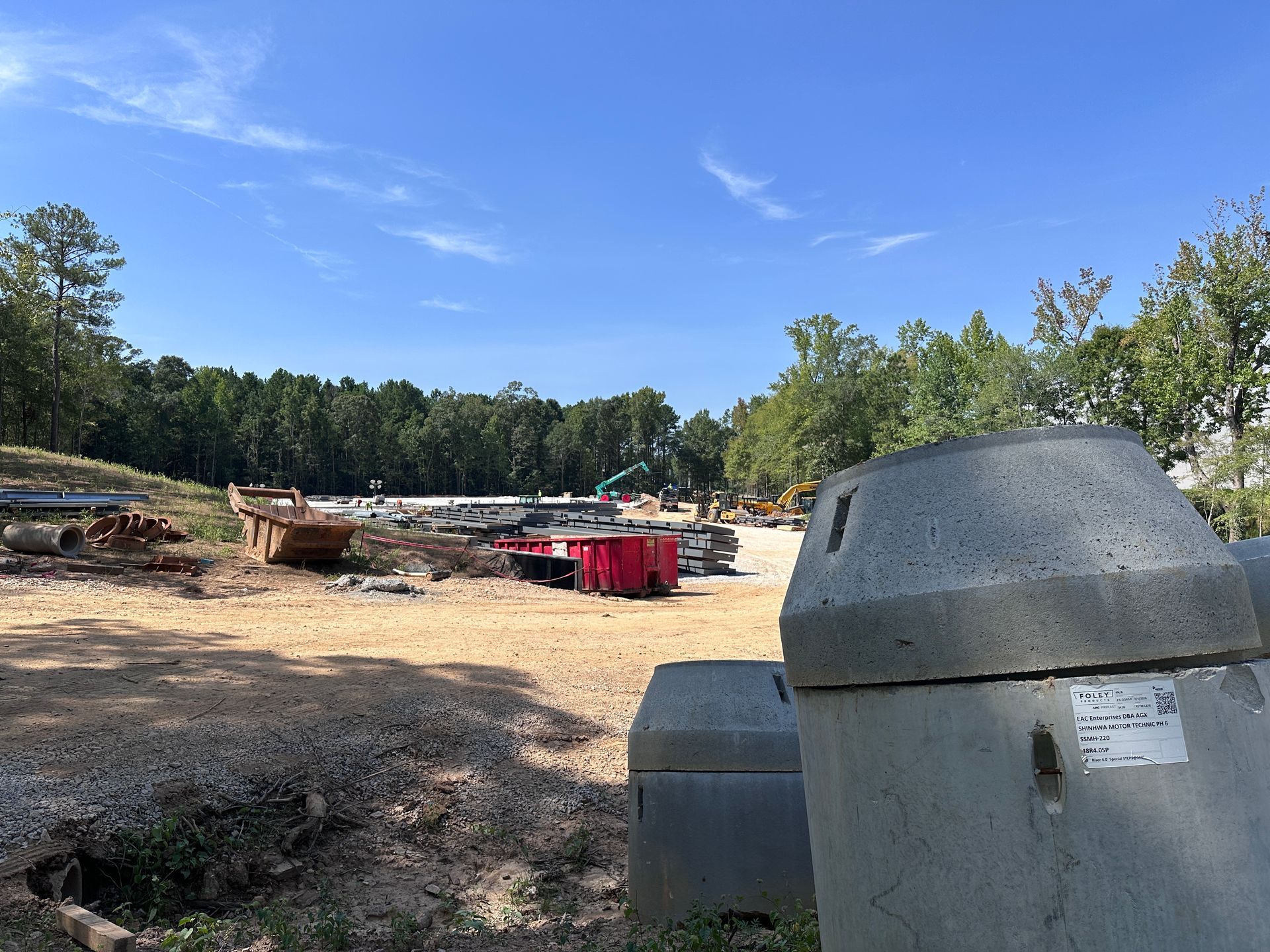 Open dirt lot with parked trailers and large gray dumpsters under a blue sky