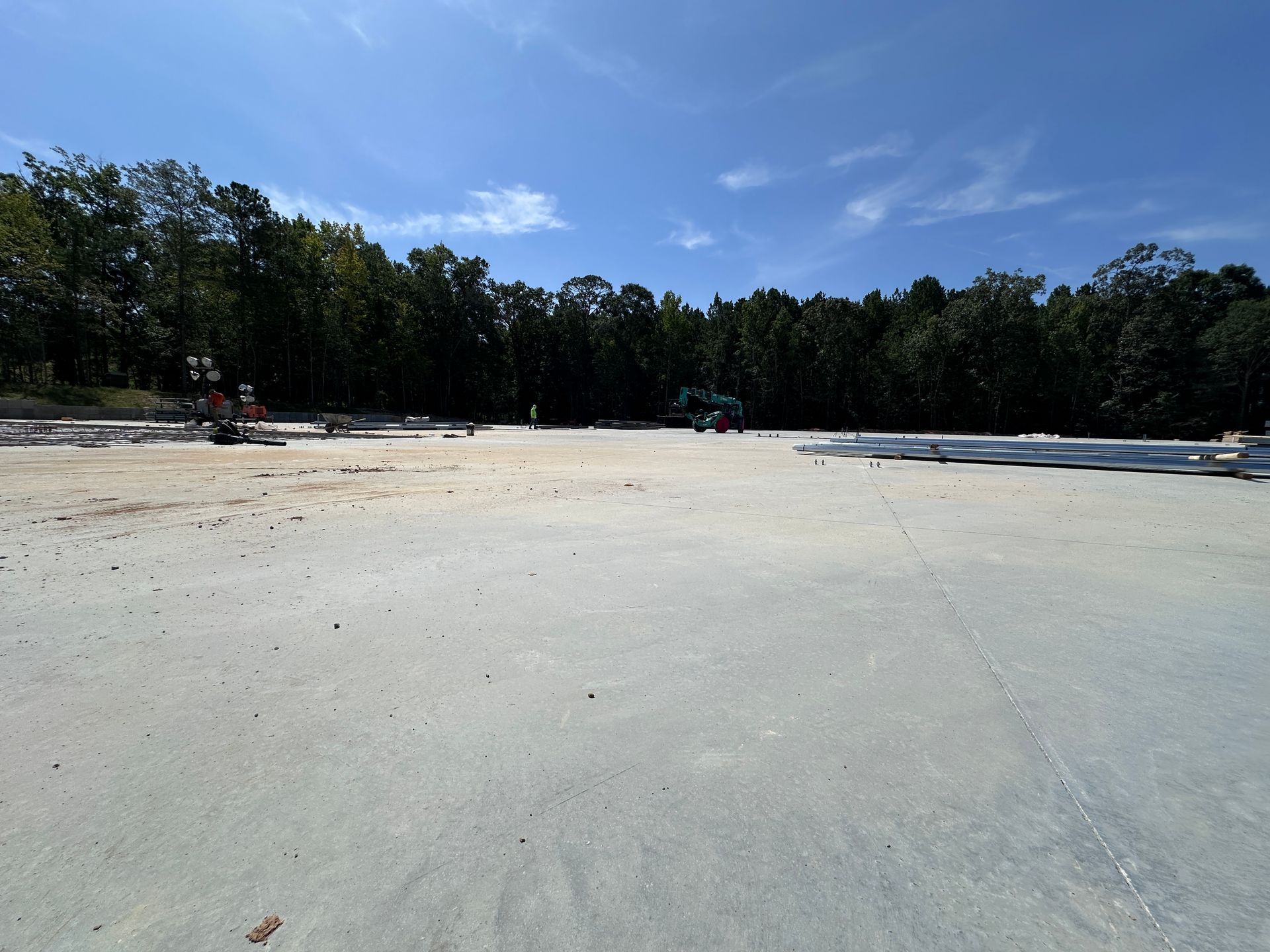Wide sandy beach with calm water, tree line, and blue sky on a sunny day