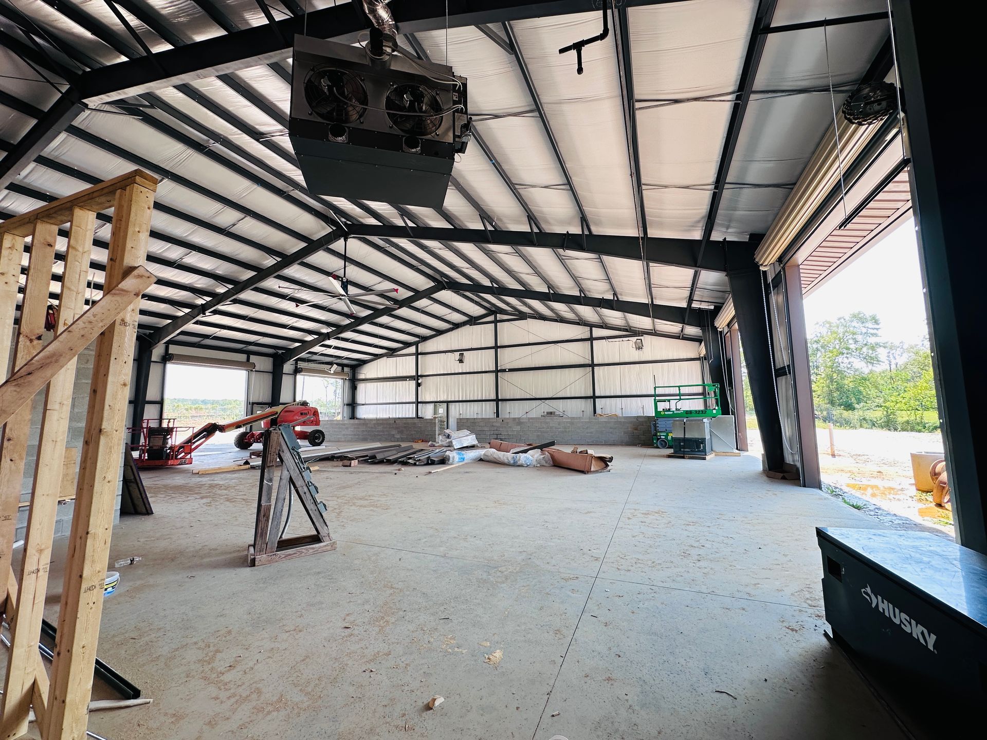 Empty steel-framed warehouse interior under construction with exposed beams and scattered materials
