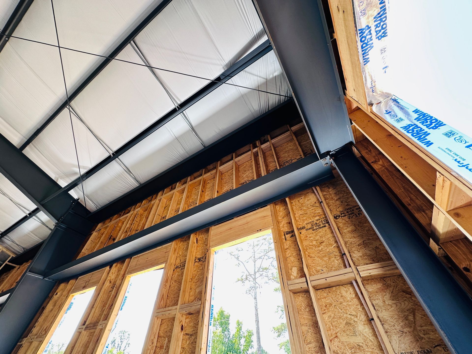 Interior of a timber-framed building under construction, with exposed beams and roof panels overhead.