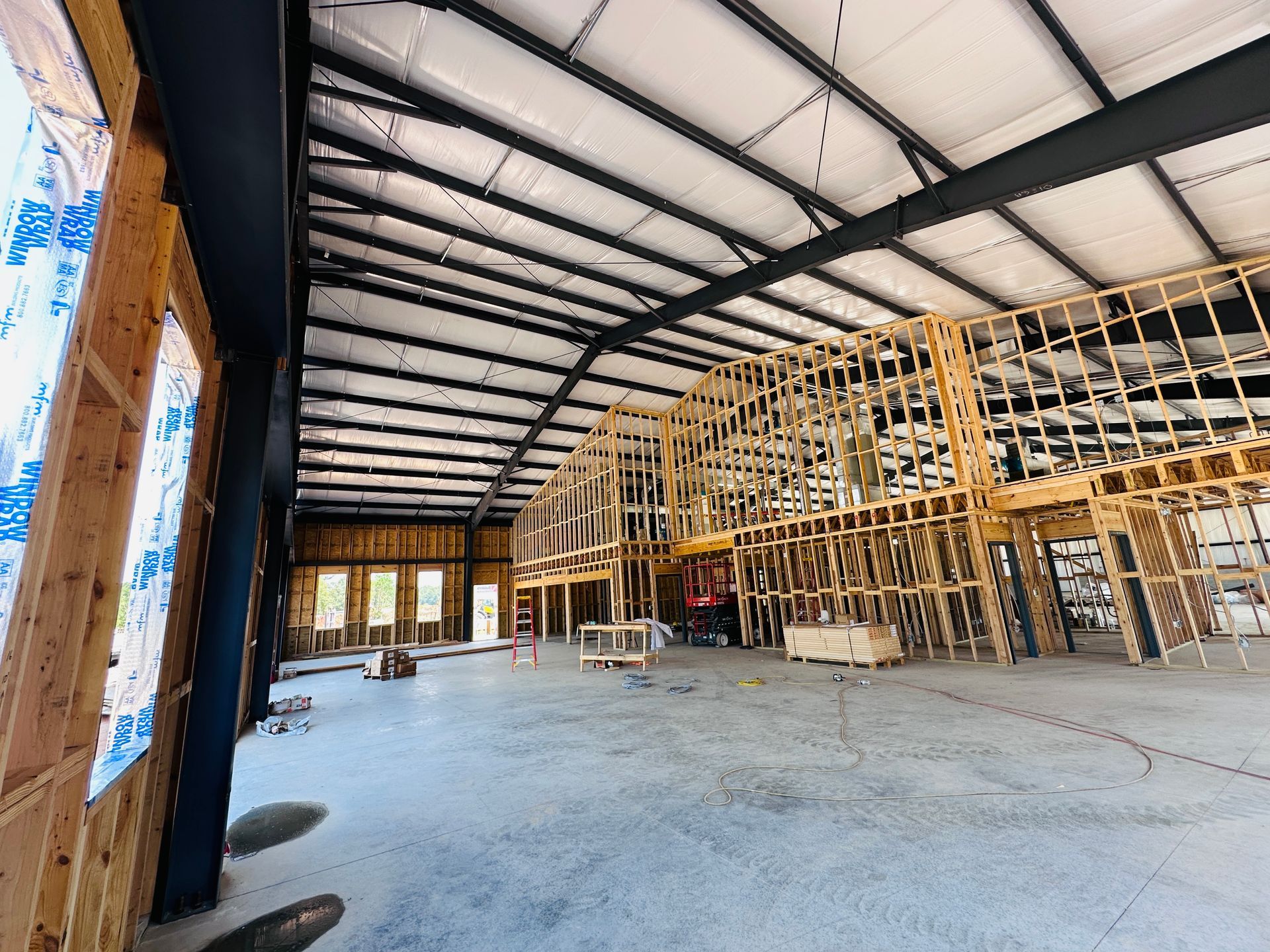 Large unfinished warehouse interior with exposed wooden framing and a concrete floor
