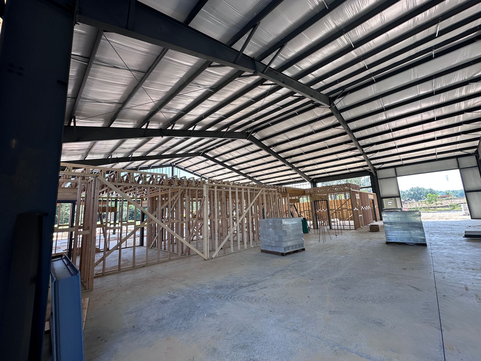 Partially built warehouse with steel roof, wooden framing, and concrete floor under construction