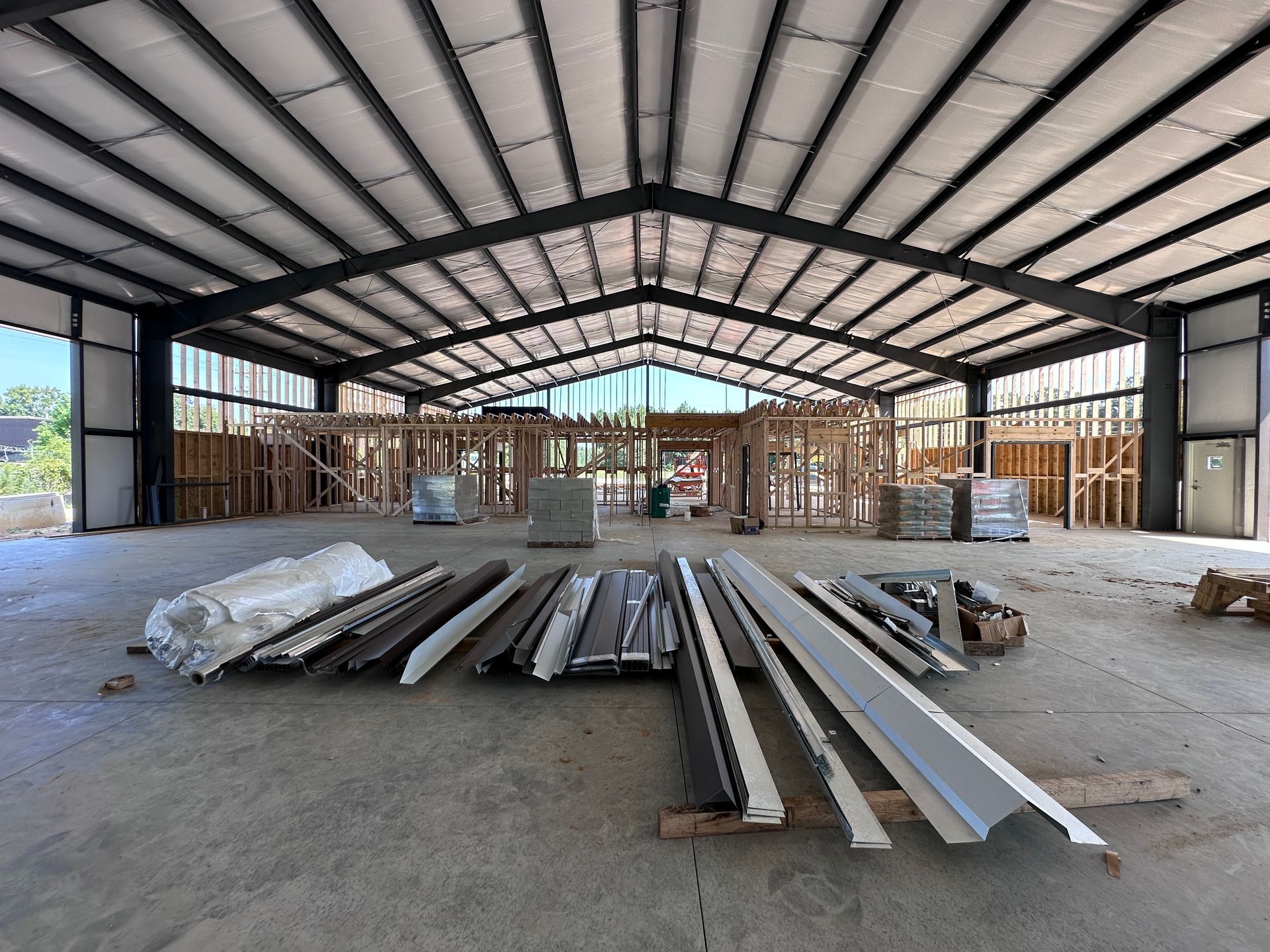 Interior of a steel building under construction with stacked metal beams on a concrete floor