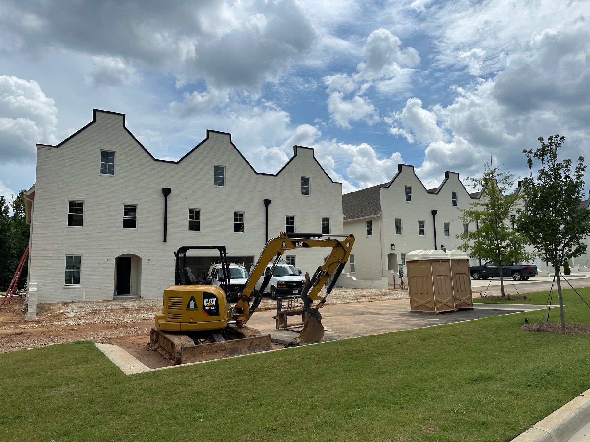 A yellow excavator is parked in front of a building under construction.