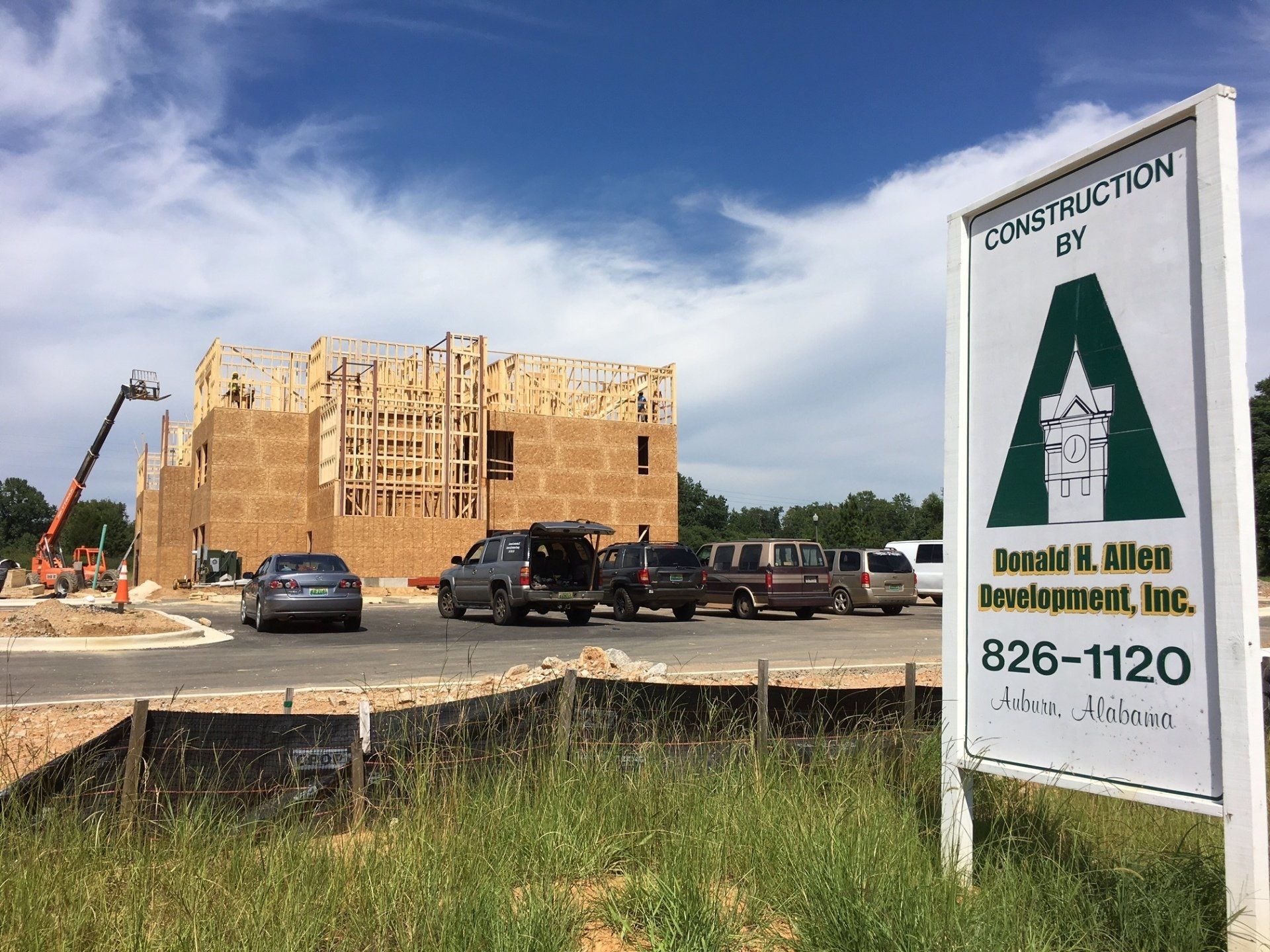 Construction site with wooden hotel framing, parked vehicles, crane, and a sign for Donald H. Allen Development, Inc.