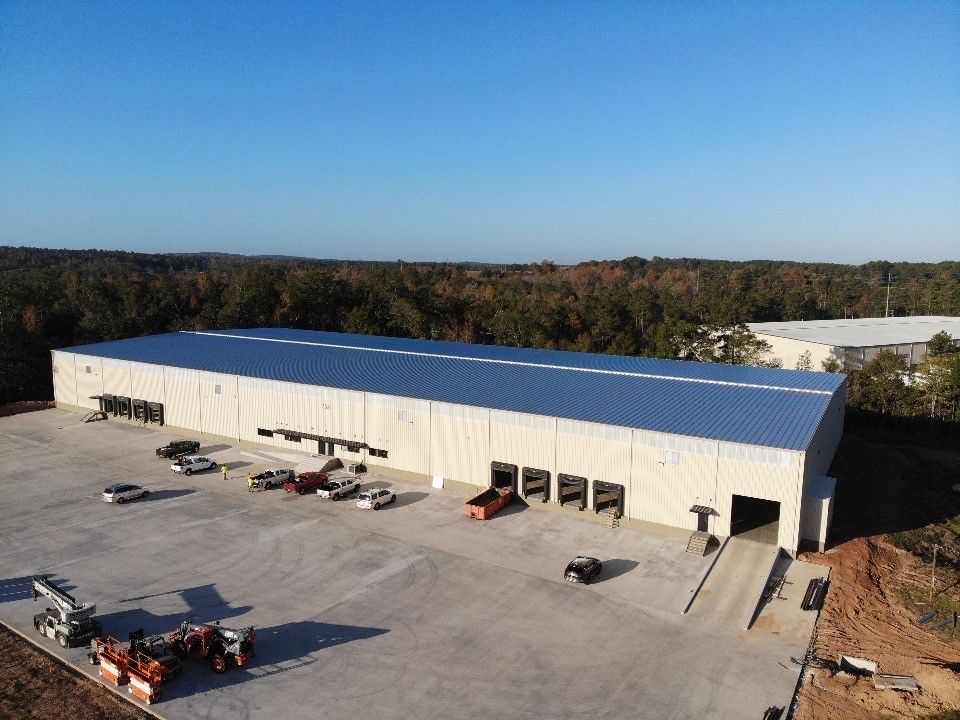 An aerial view of a large warehouse with trucks parked in front of it.