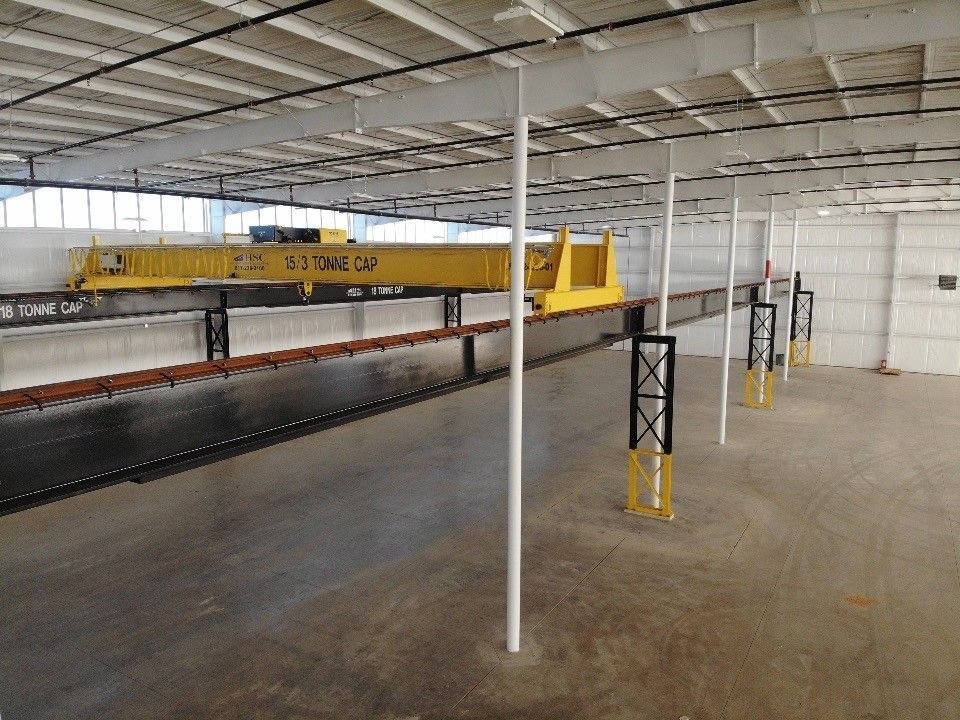 A large warehouse with a yellow crane in the middle of it.