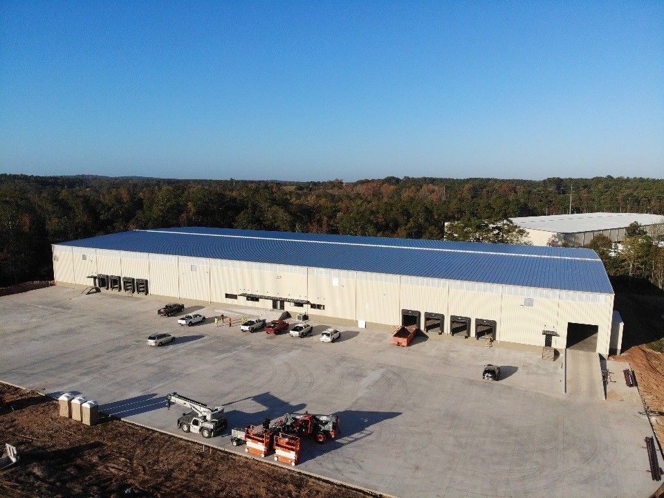 An aerial view of a large warehouse with a lot of vehicles parked in front of it.