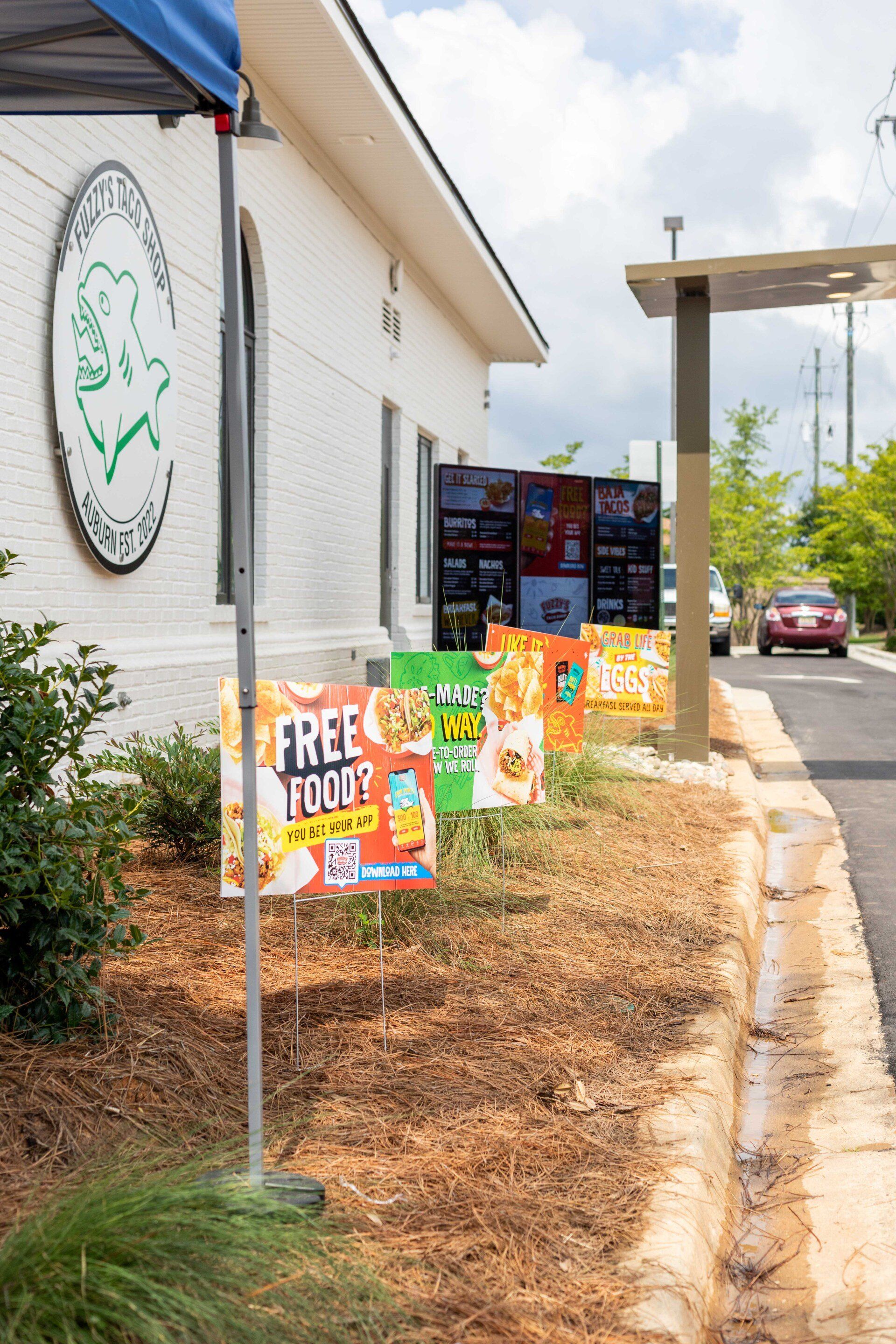A bunch of signs are sitting on the side of a road in front of a building.