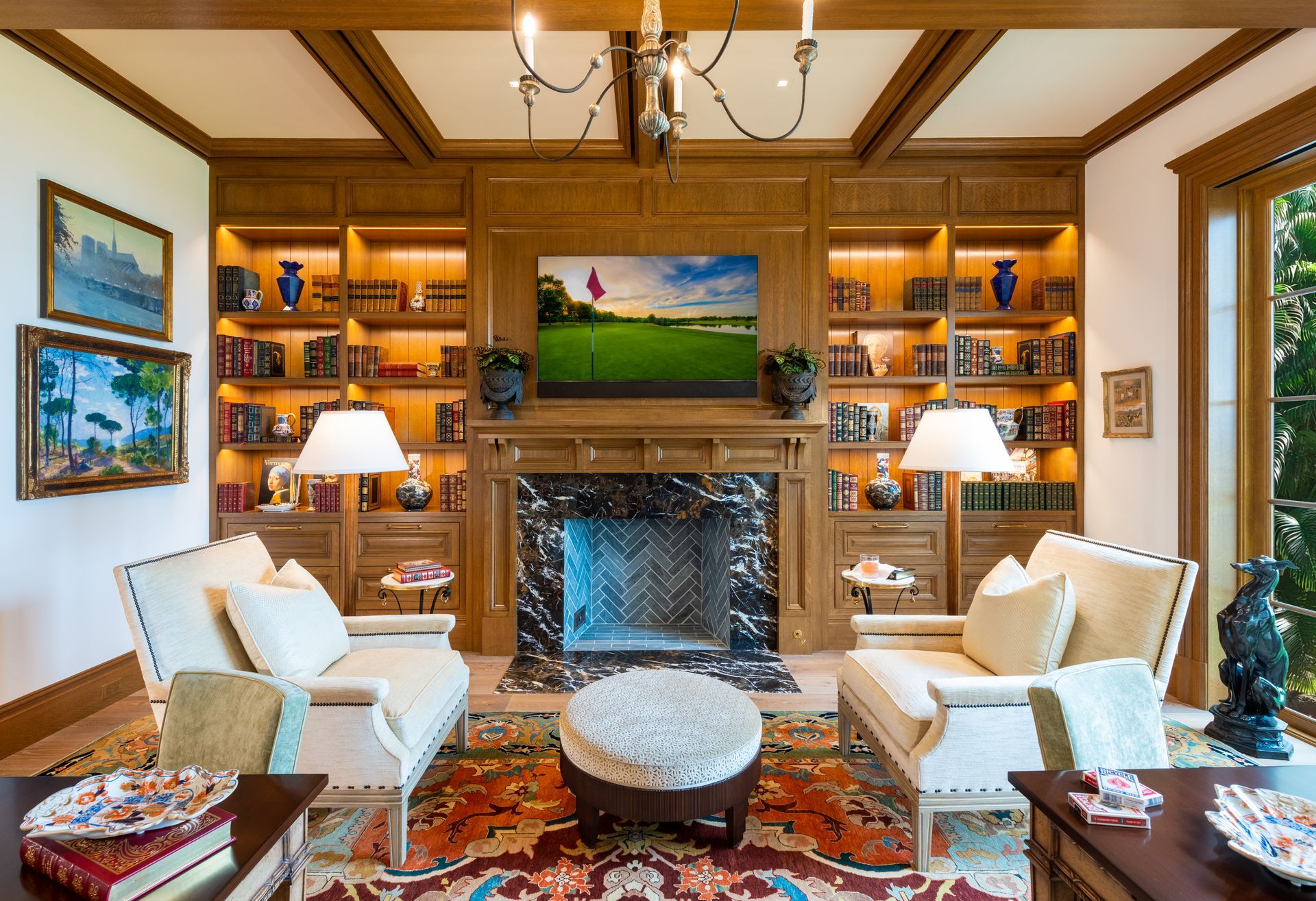 Living room with fireplace, built-in bookshelves, cream-colored couches, and a golf course scene on the TV.