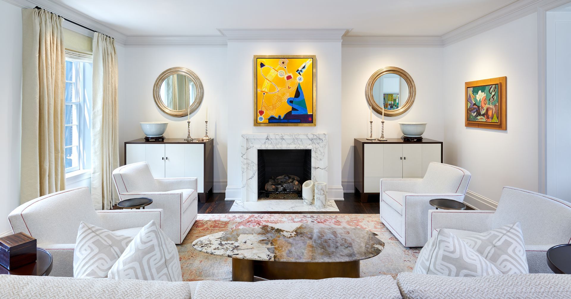 Living room with white furniture, fireplace, colorful art, and gold accents.
